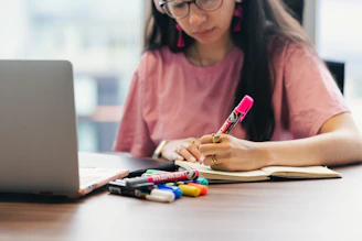 A young woman studying and writing notes at a desk.