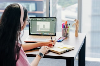 Woman wearing headphones studies at a desk.