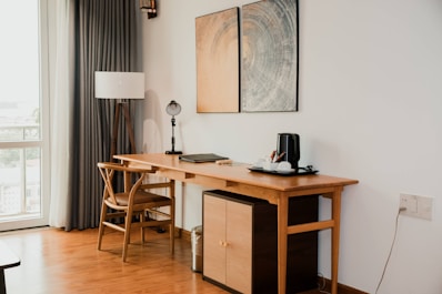 A wooden desk with a chair and lamp.