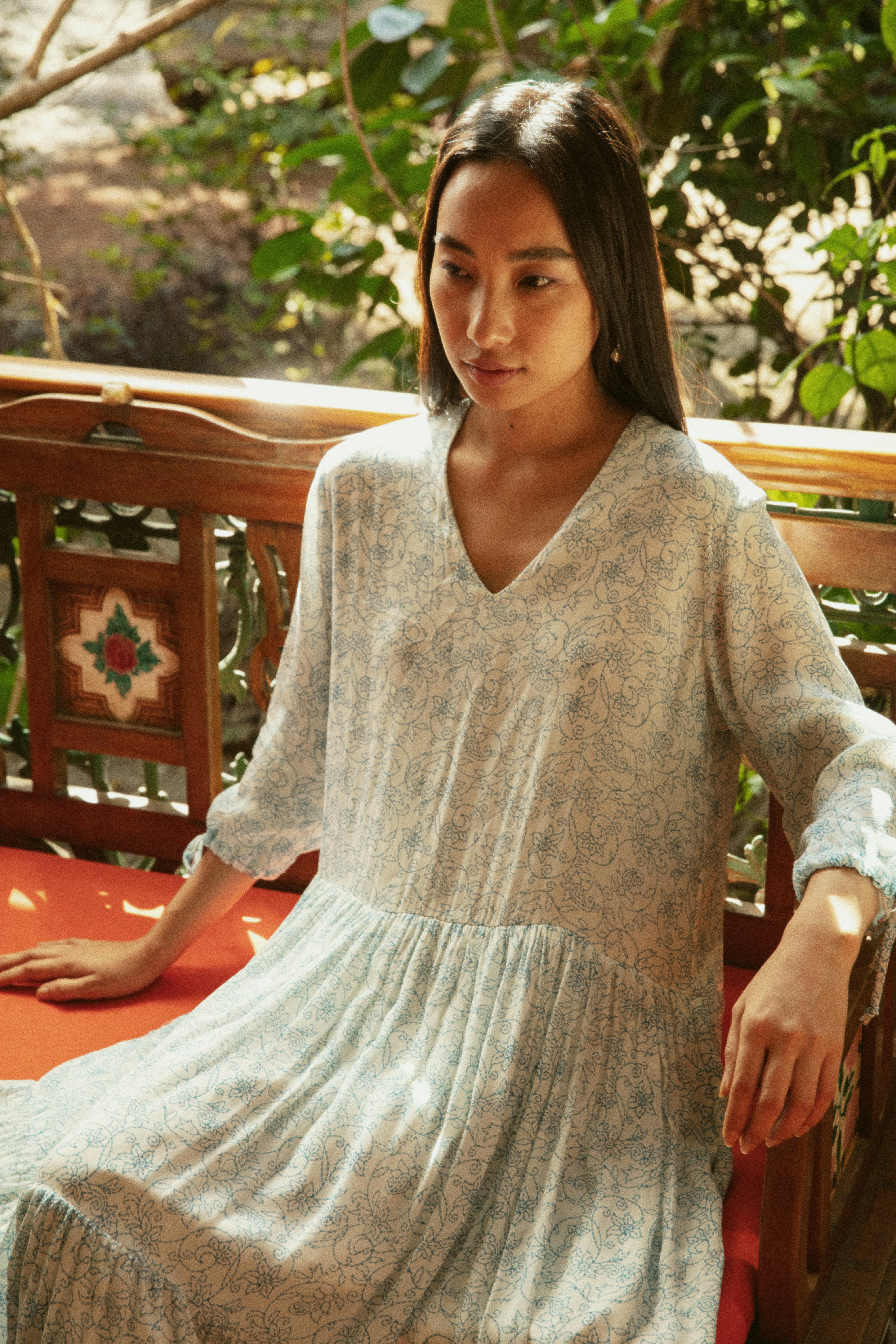 Young woman in a patterned dress sitting outdoors