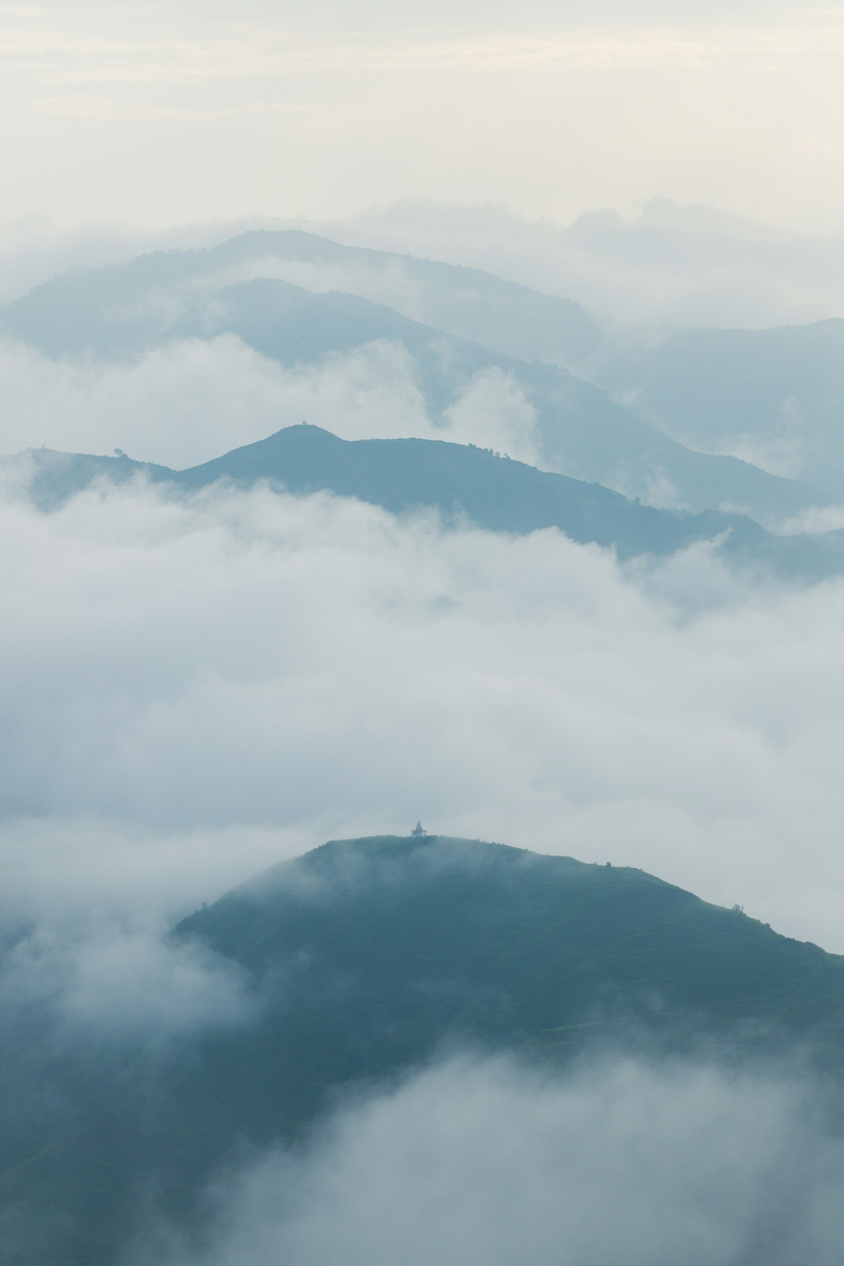 Misty mountains shrouded in soft clouds at dawn.