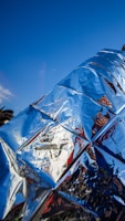 Shiny metallic surface reflects blue sky and red colors.