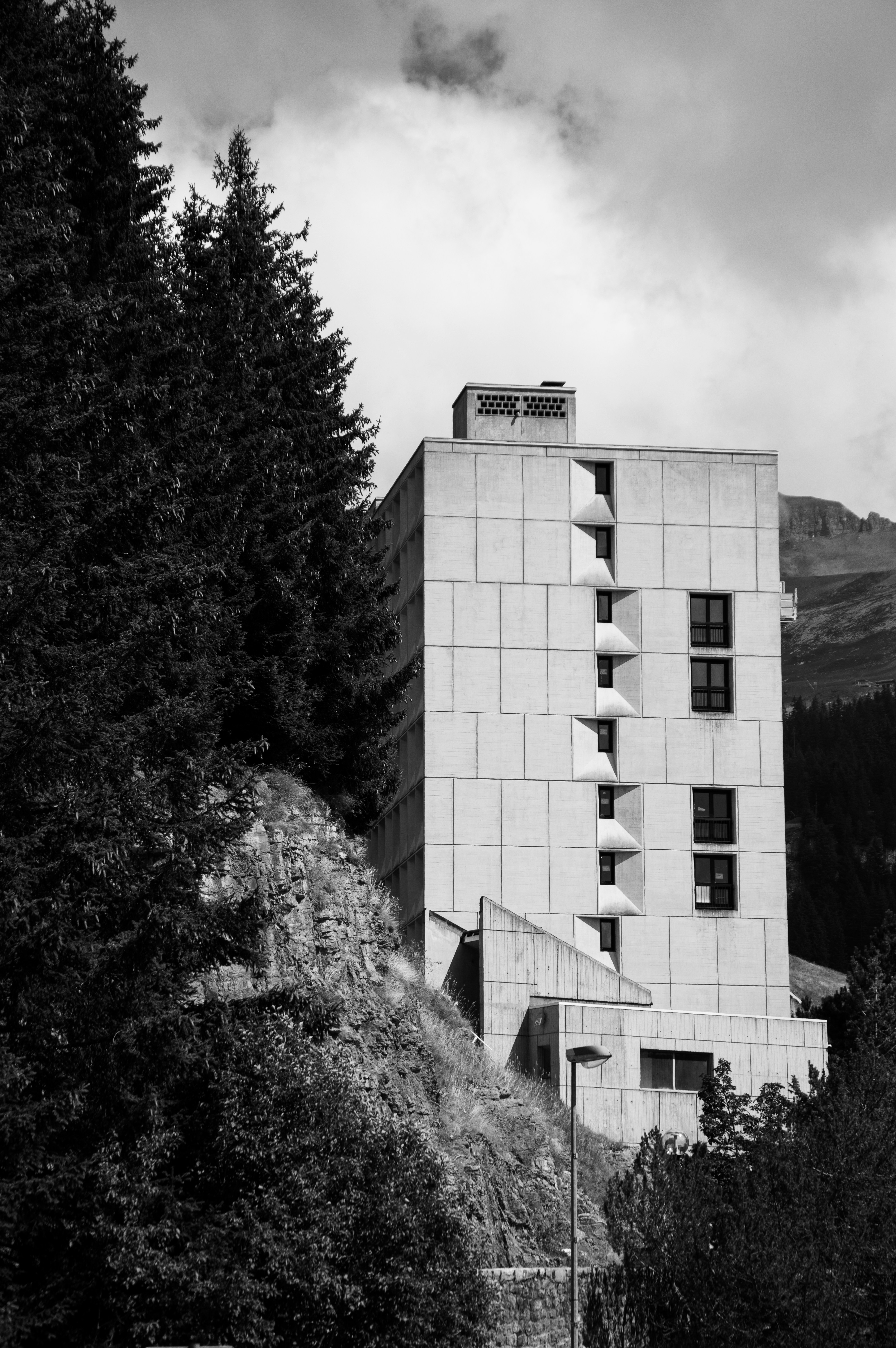 Edificio moderno incastonato tra alberi e montagne.