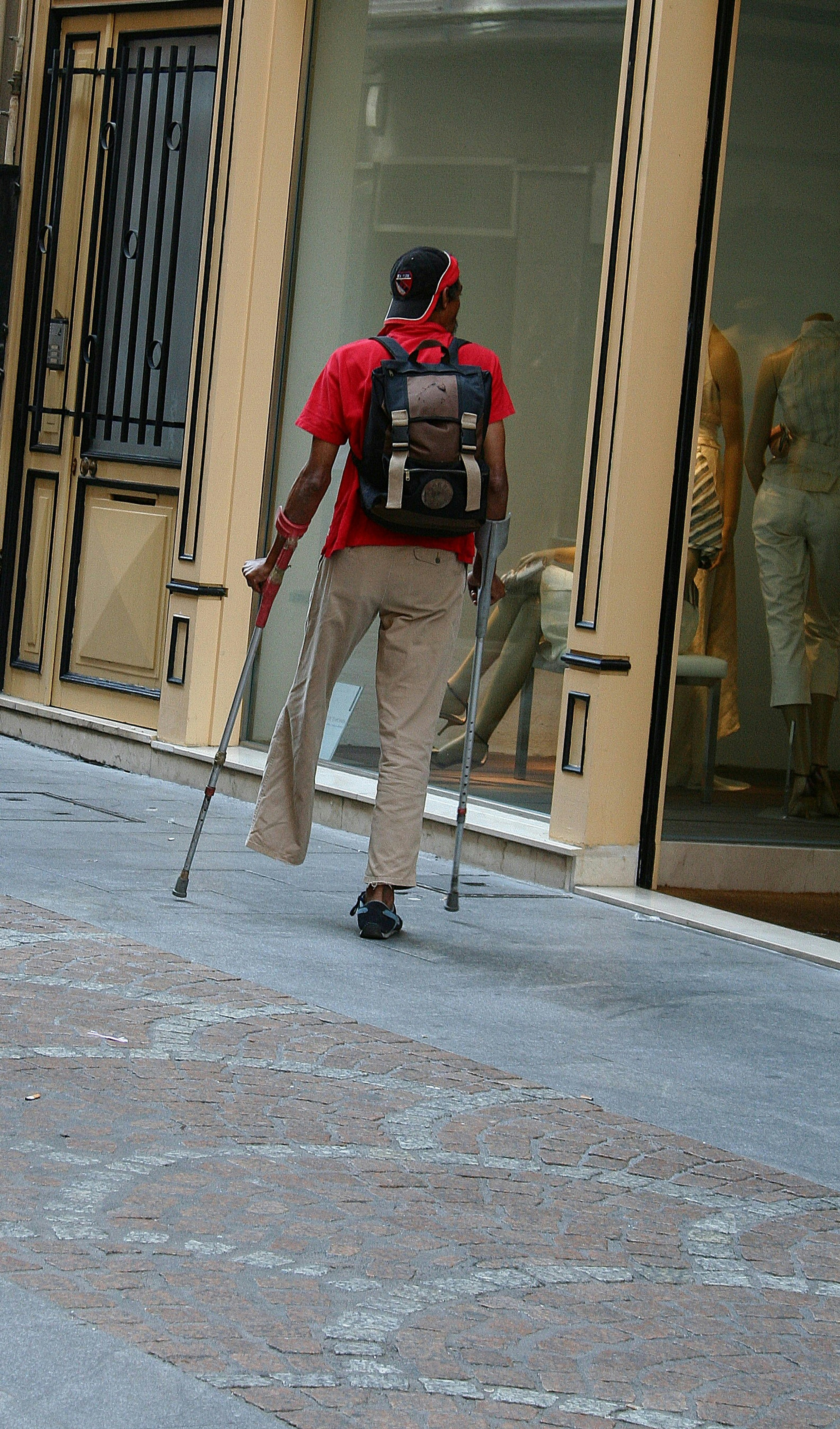Man with crutches walks past storefront window