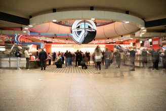 People in a busy, modern train station concourse.