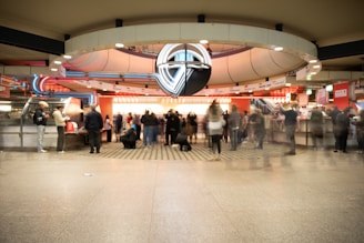People in a busy, modern train station concourse.