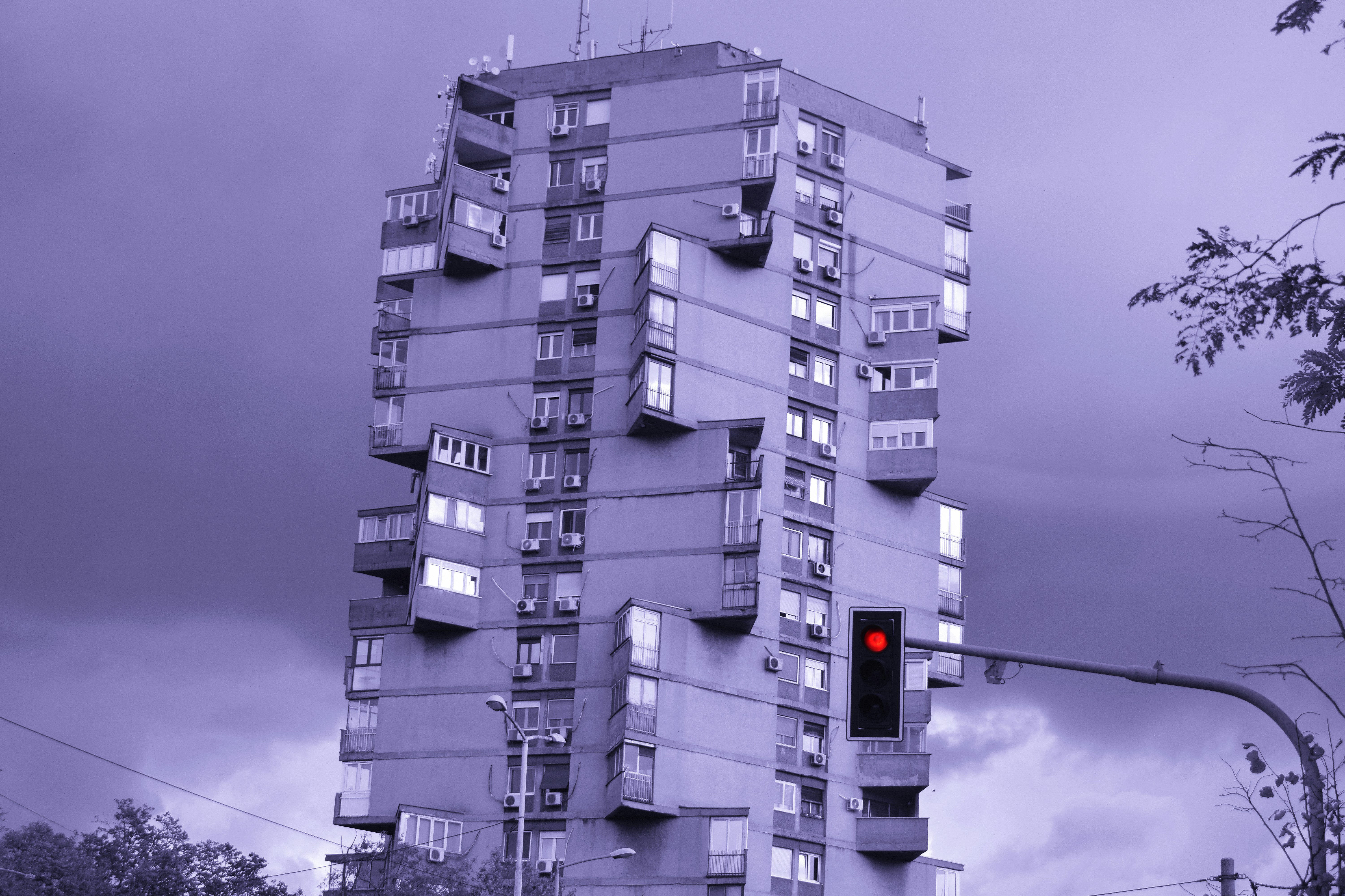 Tall apartment building with balconies under stormy sky