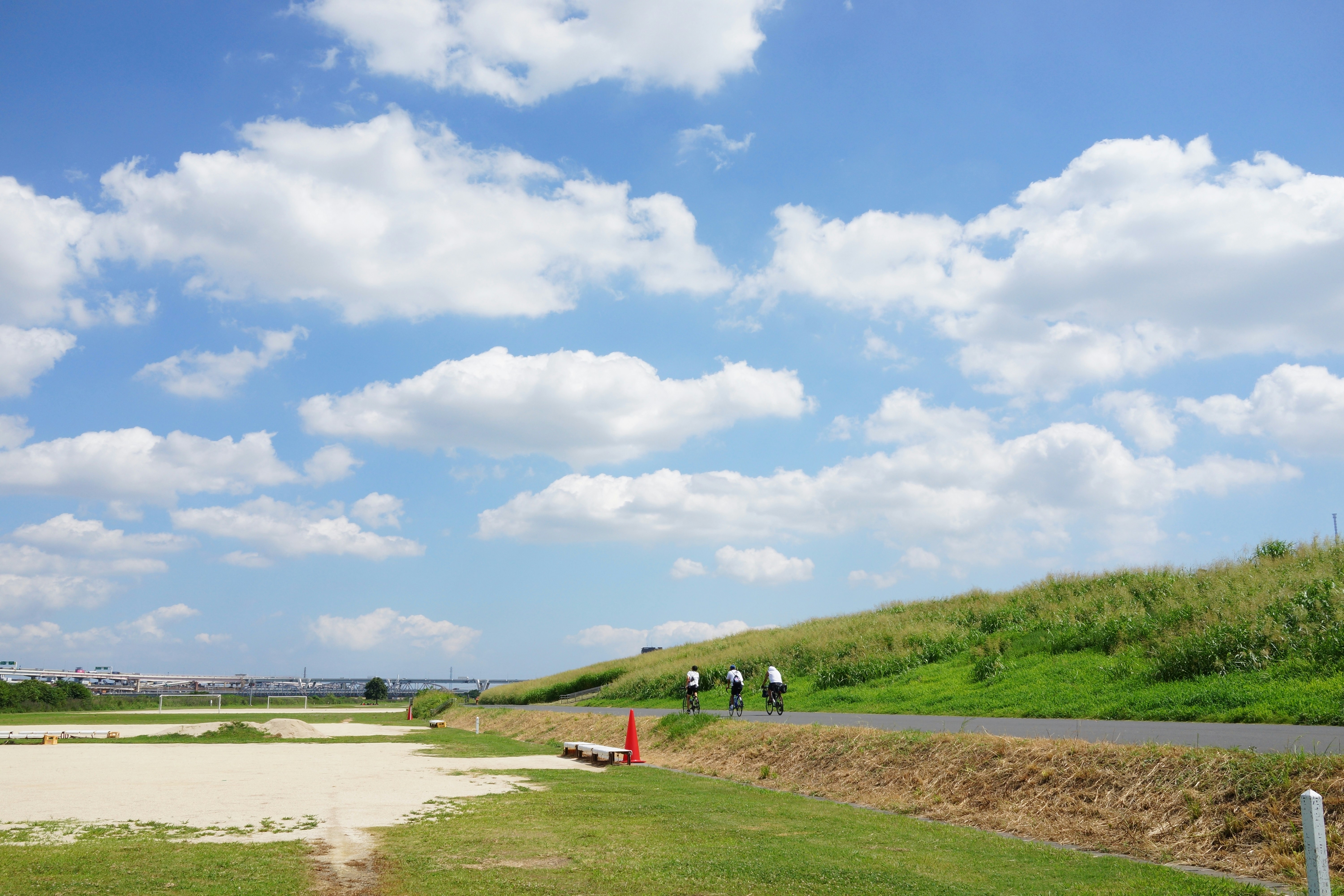 People cycling on a path beside a grassy hill