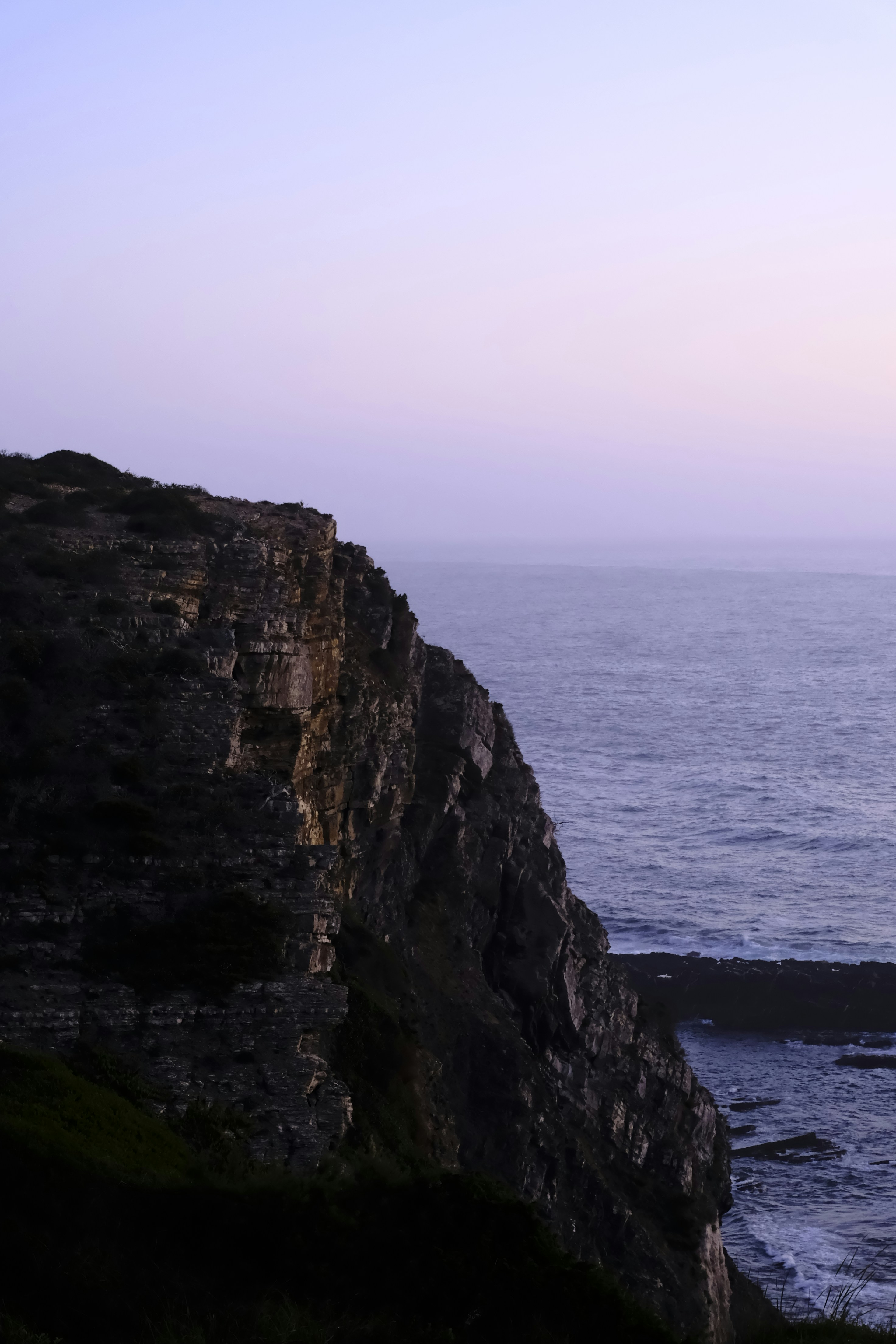 Rocky cliff overlooking the ocean at dusk