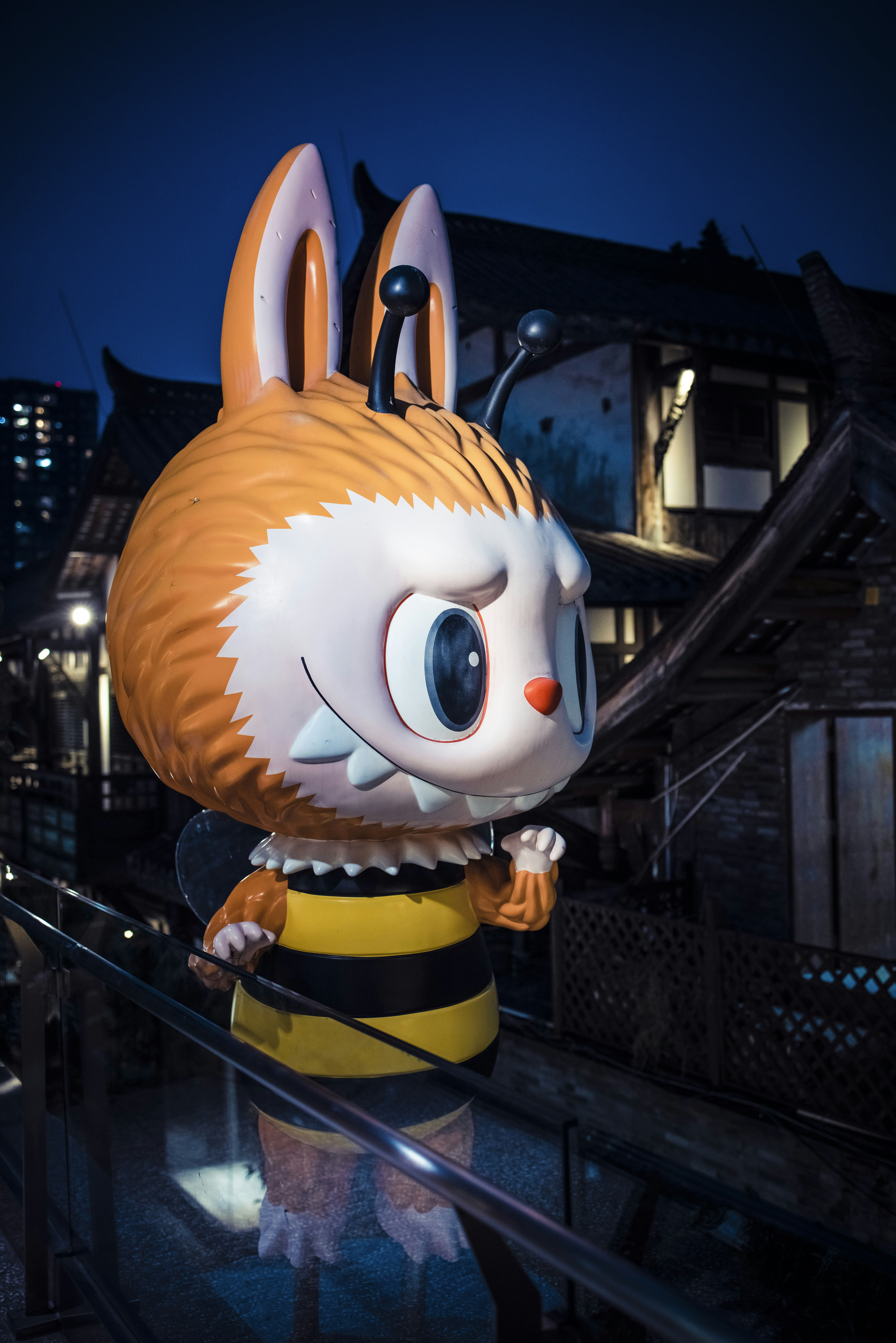 A cartoon bee character statue at night