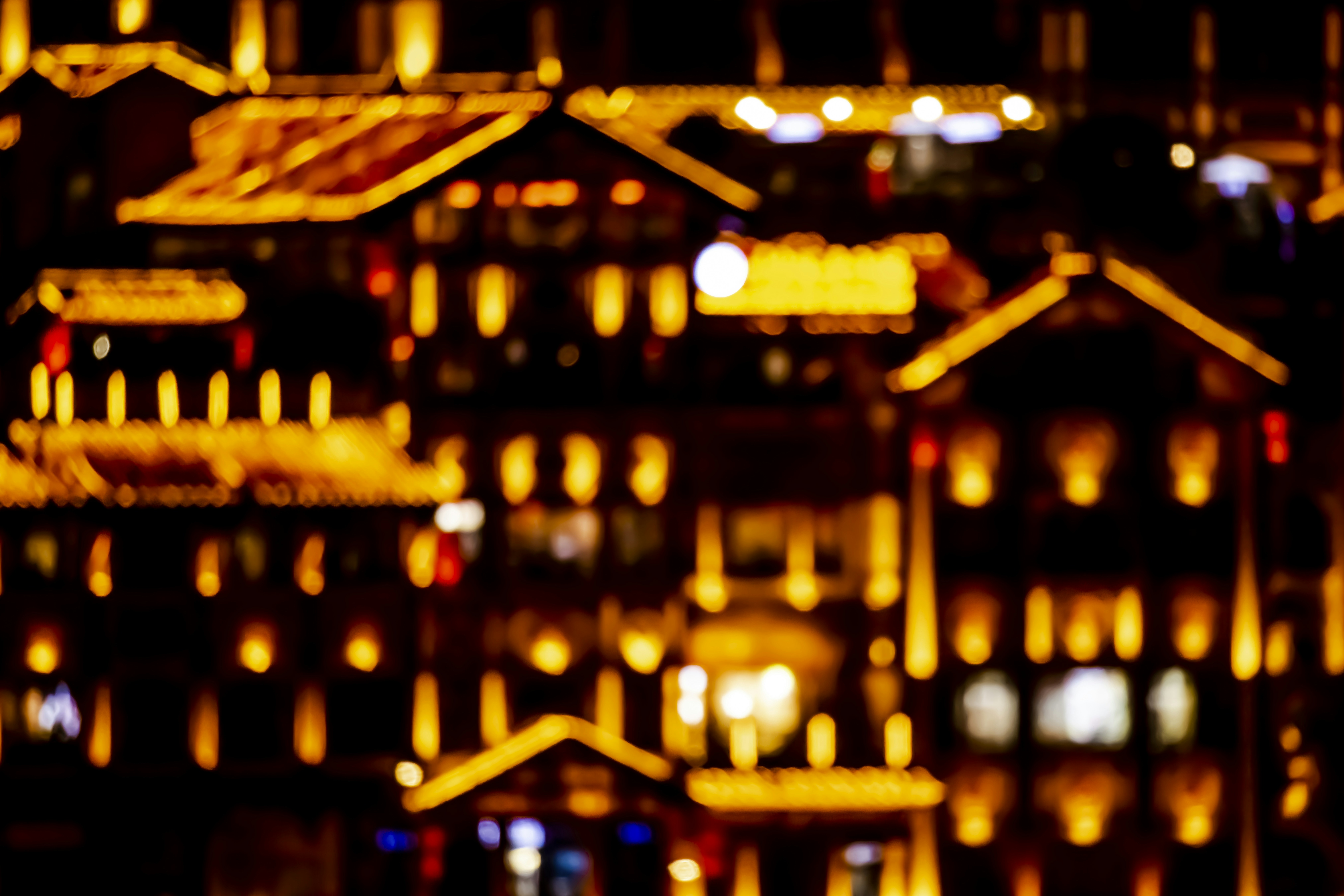 Blurred buildings illuminated by warm lights at night.