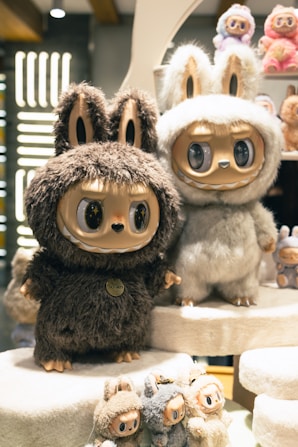 Two fuzzy stuffed toys with large eyes.