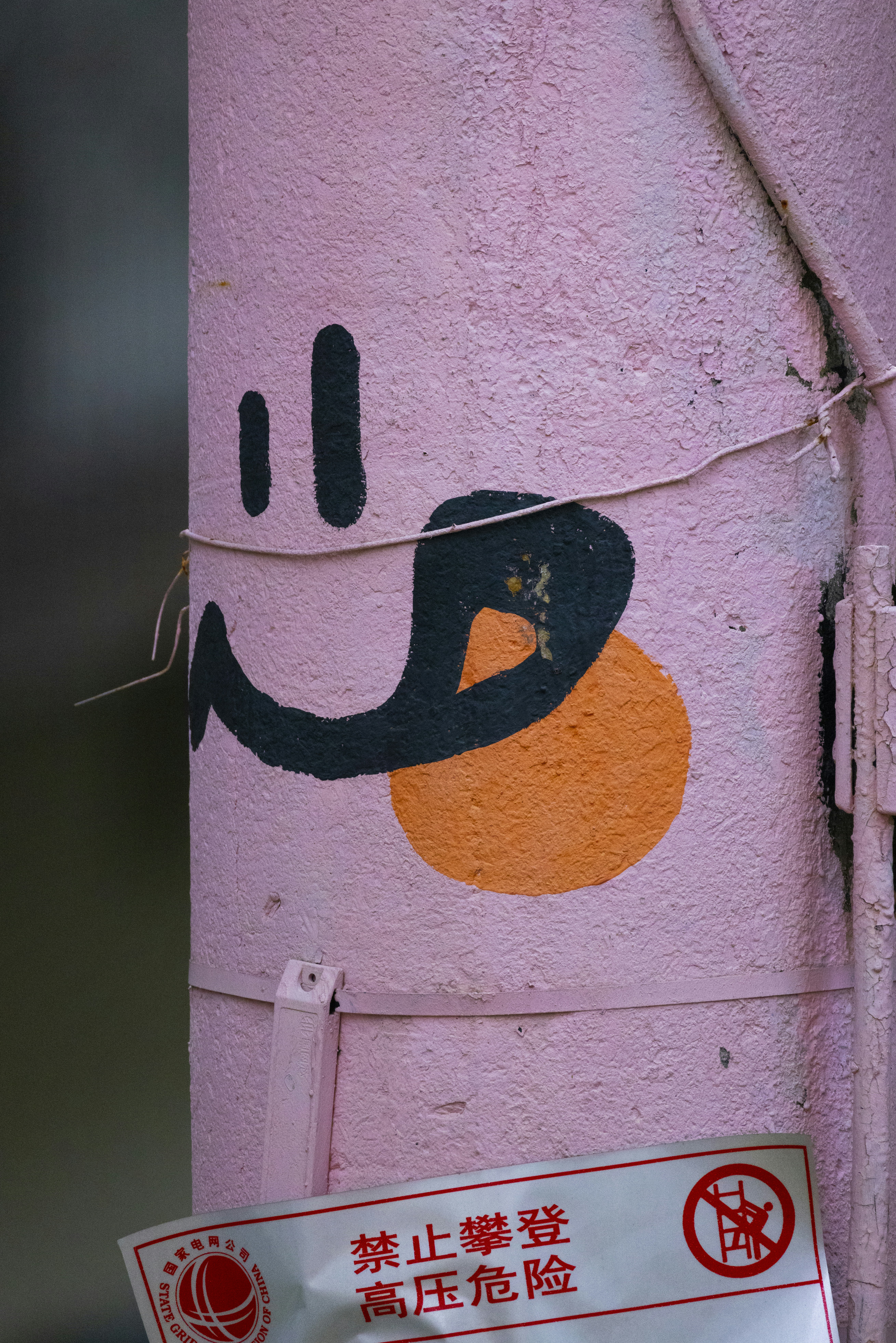 Pink pole with a black smiley face and orange circle.