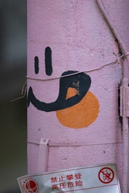 Pink pole with a black smiley face and orange circle.