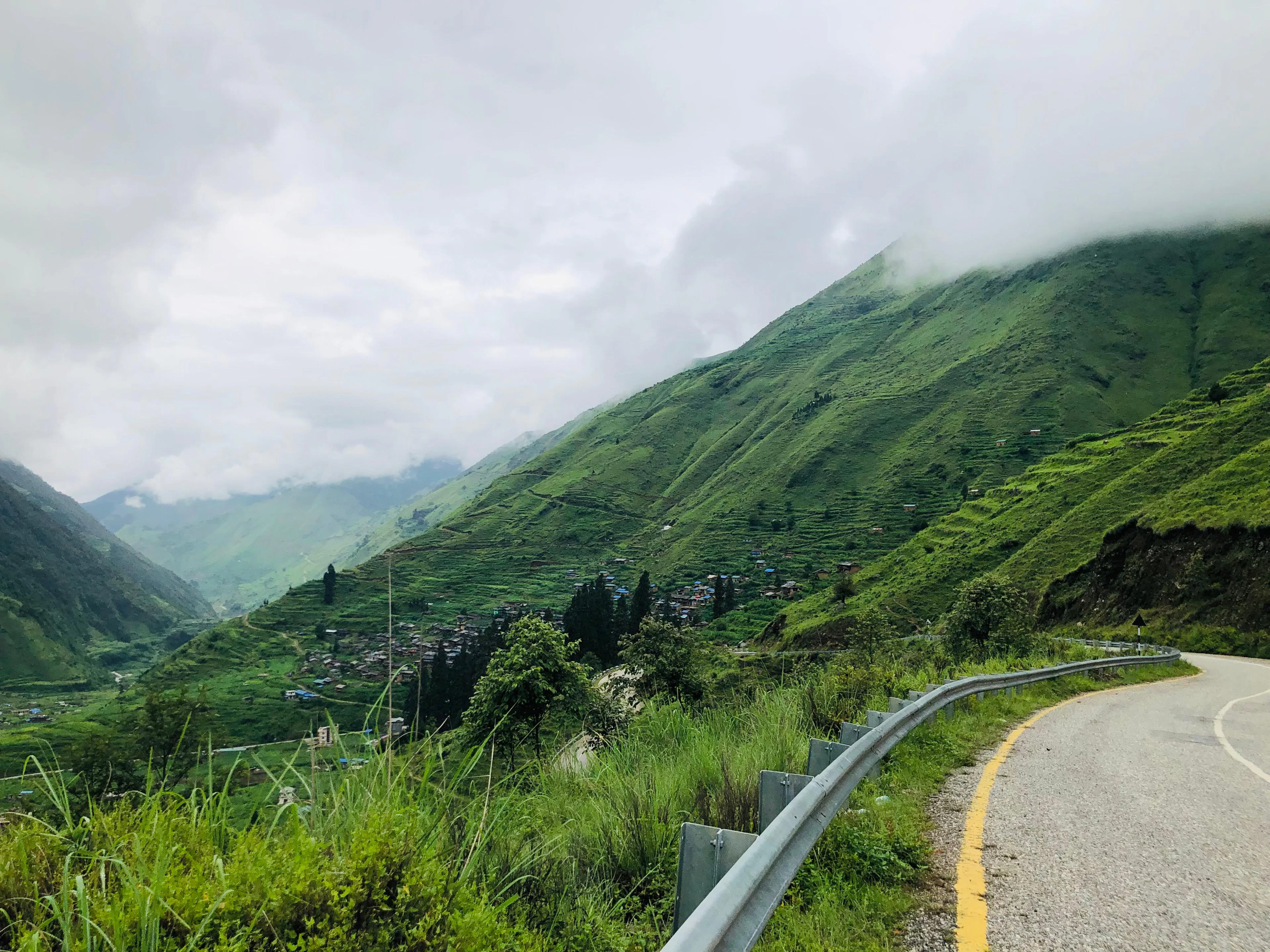 Road curving past green terraced hillsides and a village