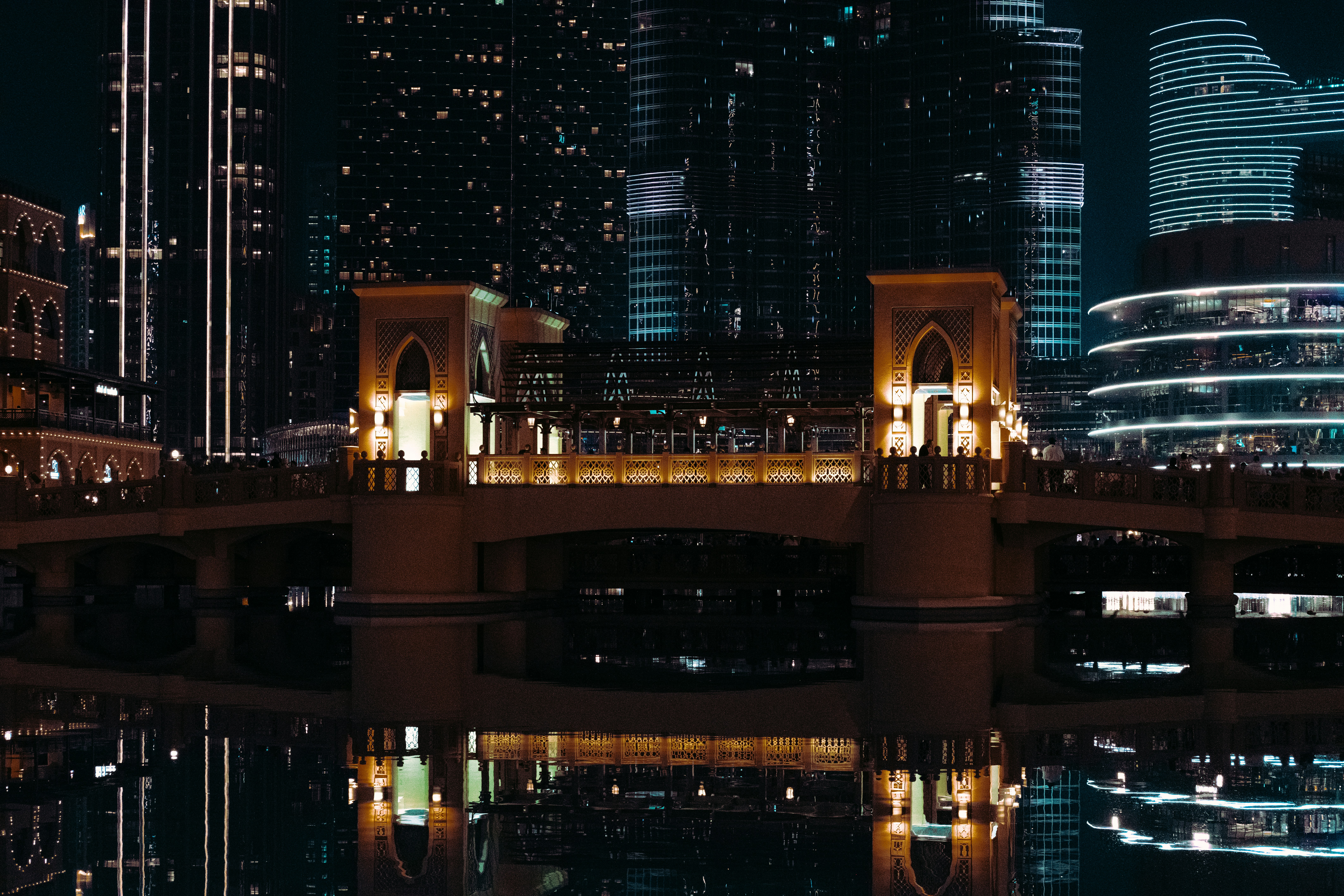 Modern cityscape with illuminated bridge over water at night