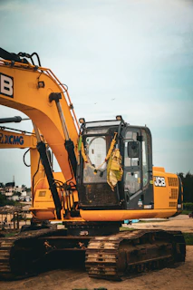 Yellow excavator parked on sandy ground outdoors