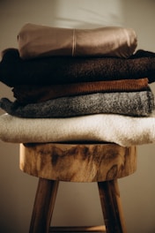 Stack of folded cozy sweaters on wooden stool