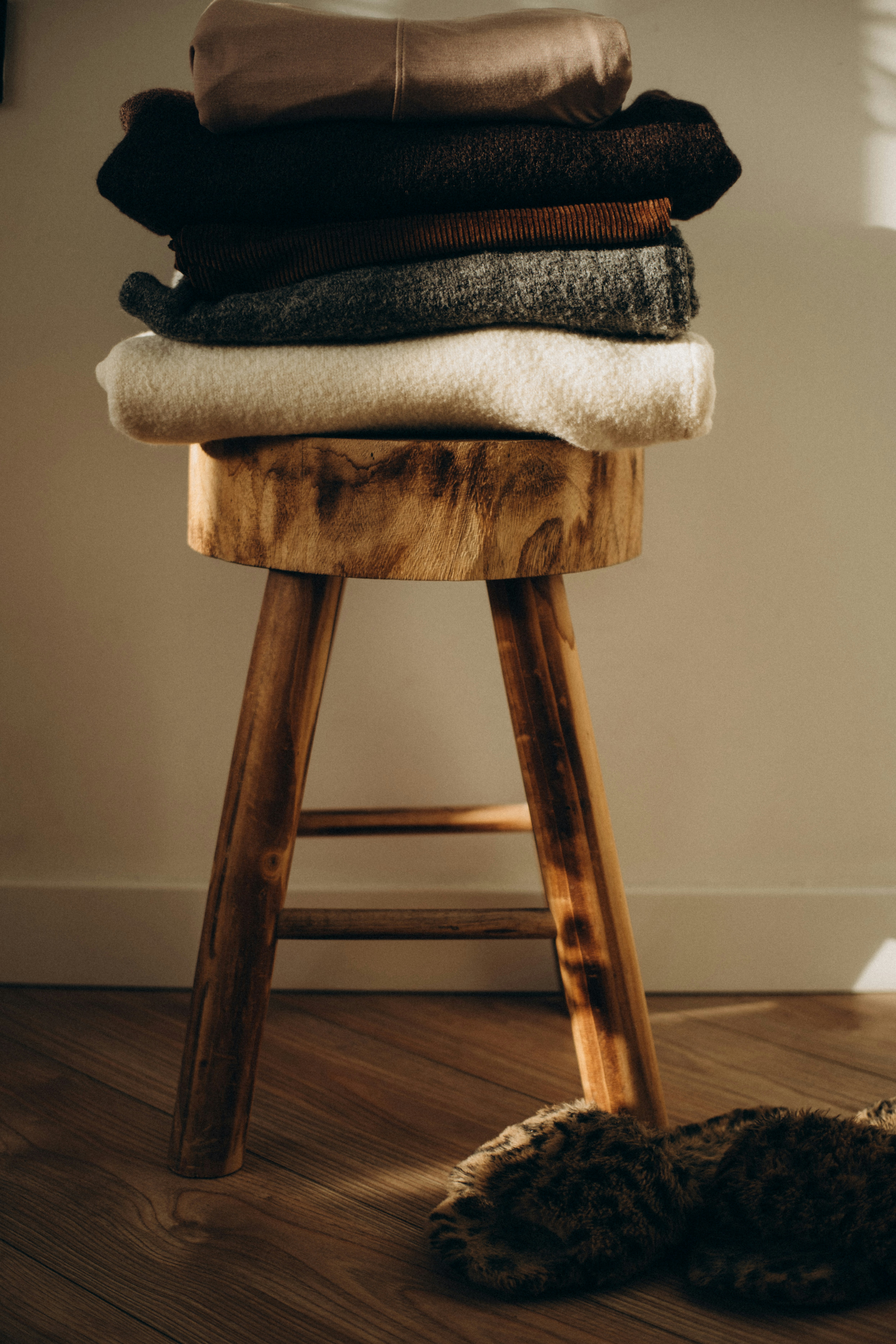 Stack of folded sweaters on a wooden stool