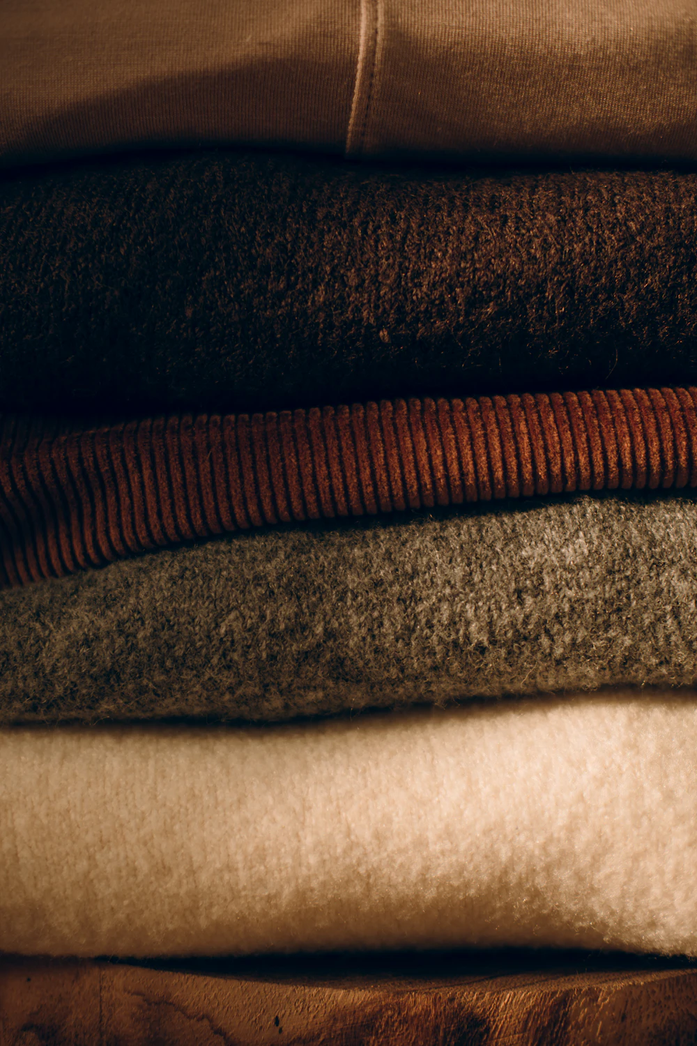 Stack of folded wool sweaters in rich earth tones