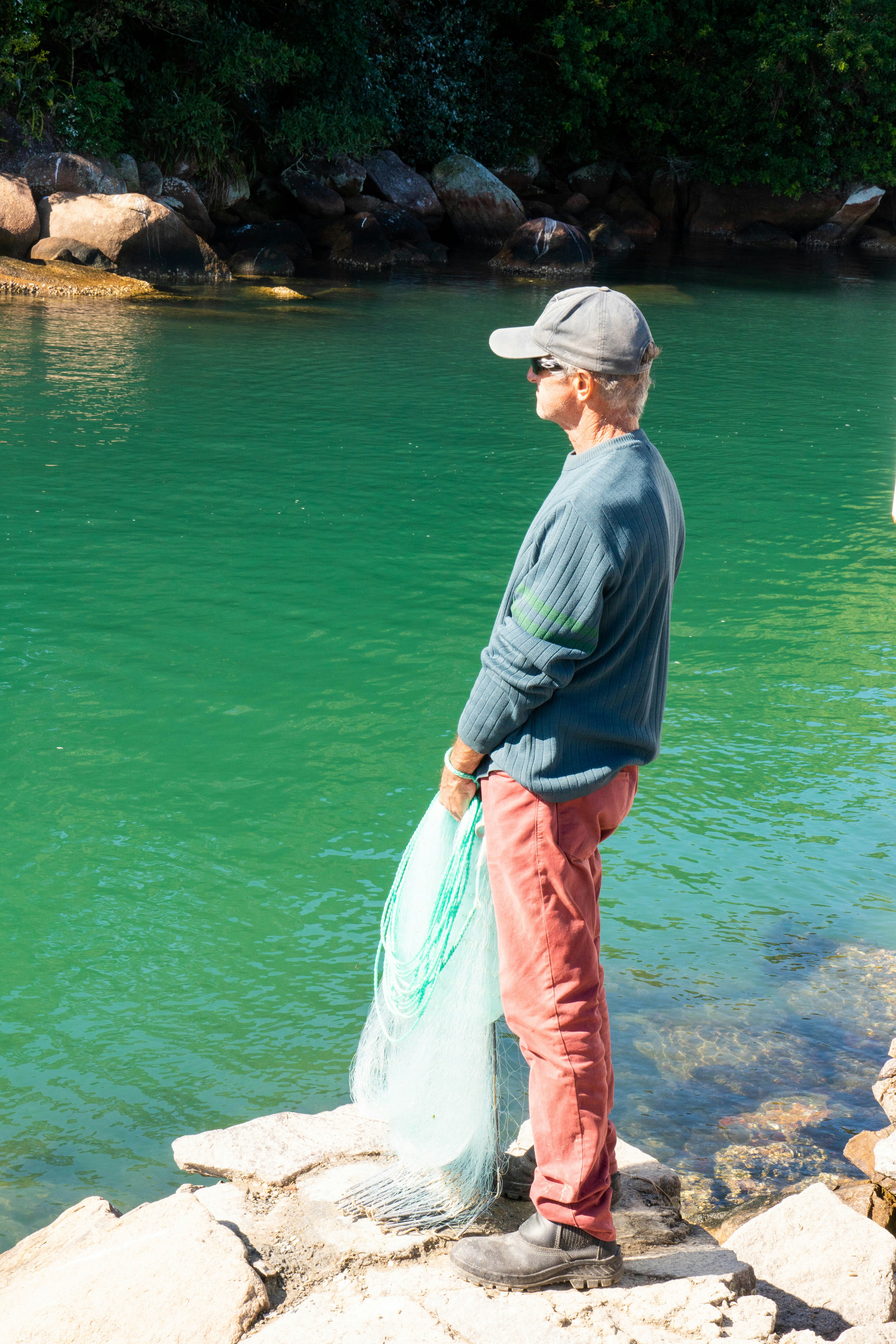 Man with fishing net by turquoise water