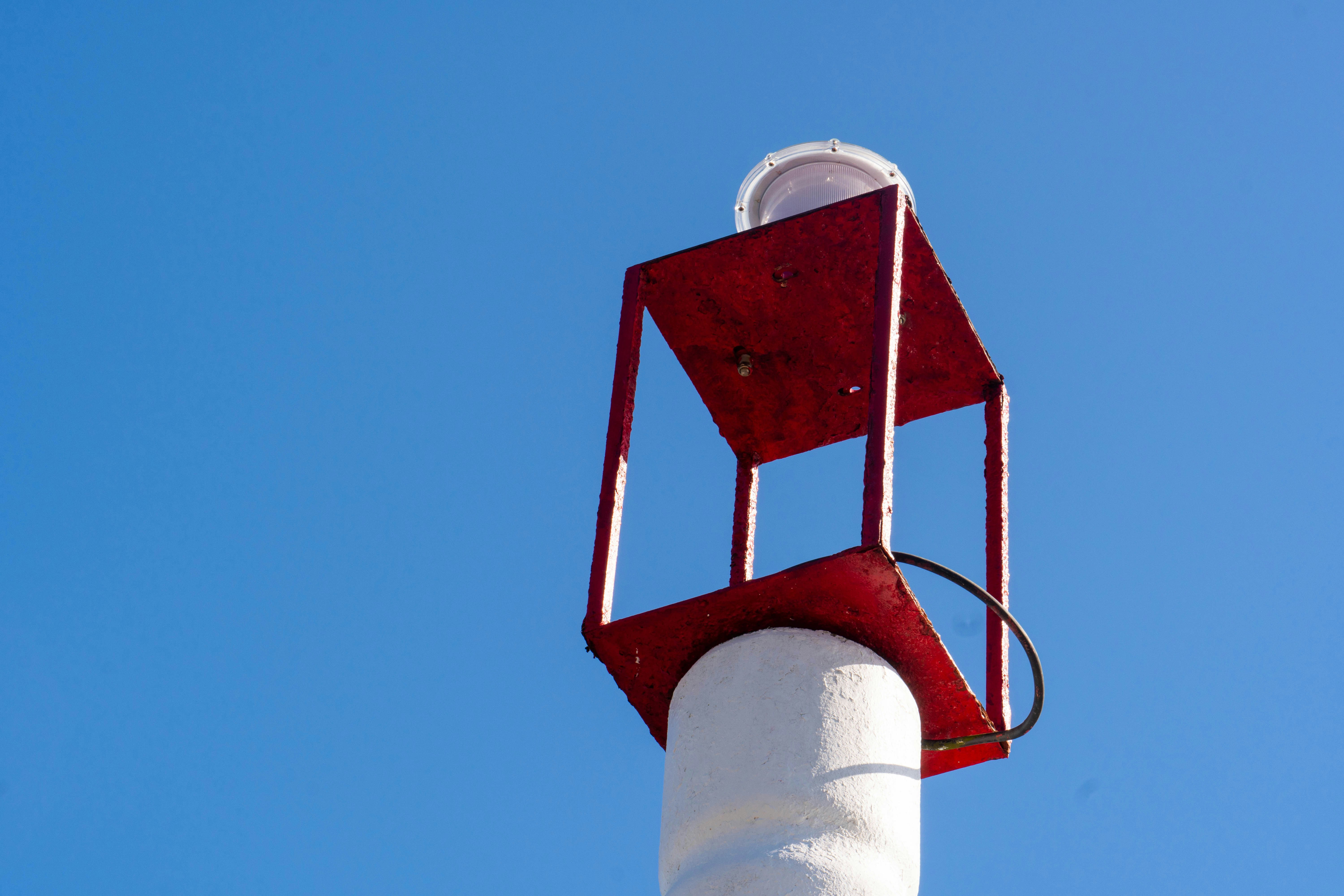 Red metal frame on white pole under blue sky