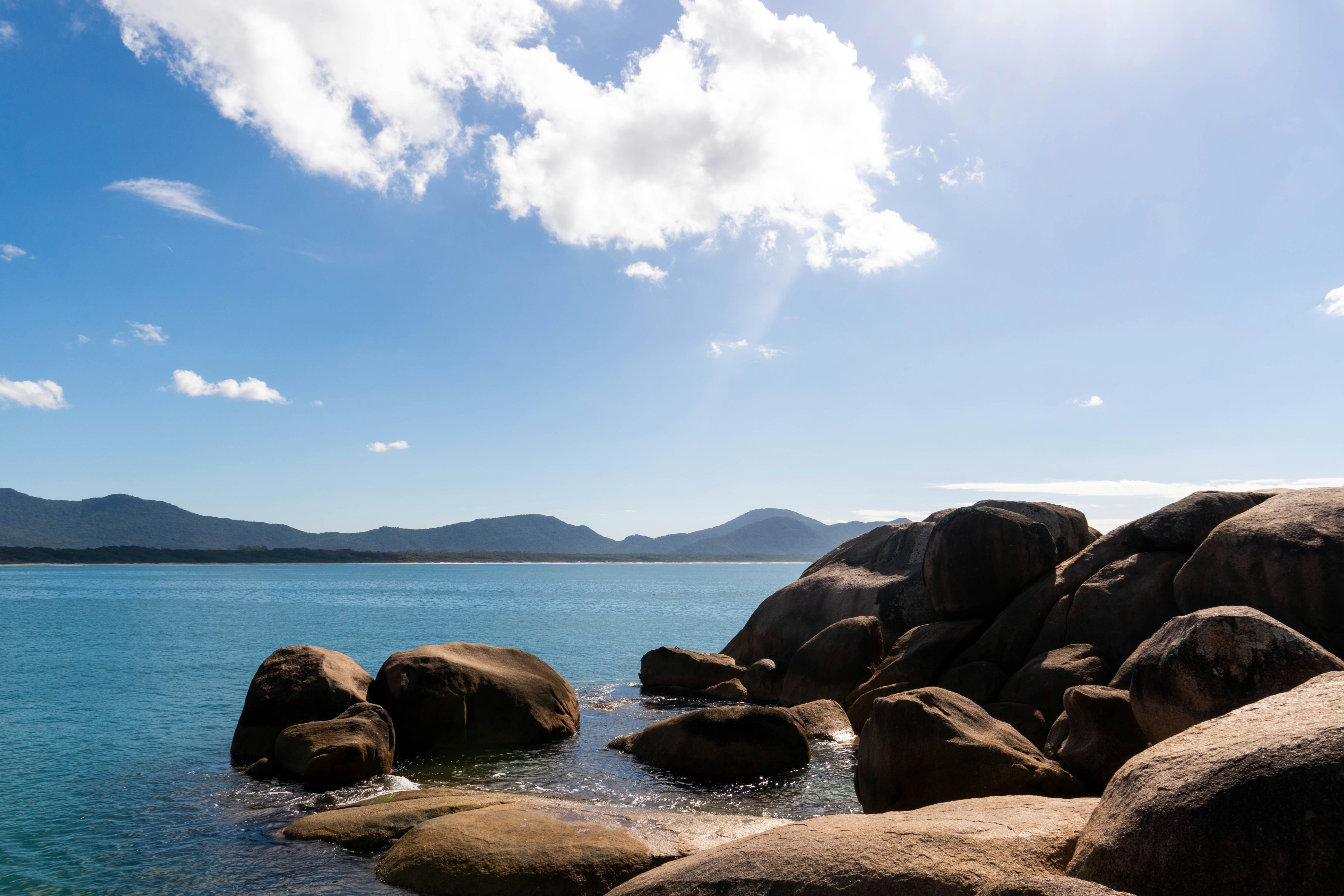 Large boulders on a rocky coastline with blue ocean.
