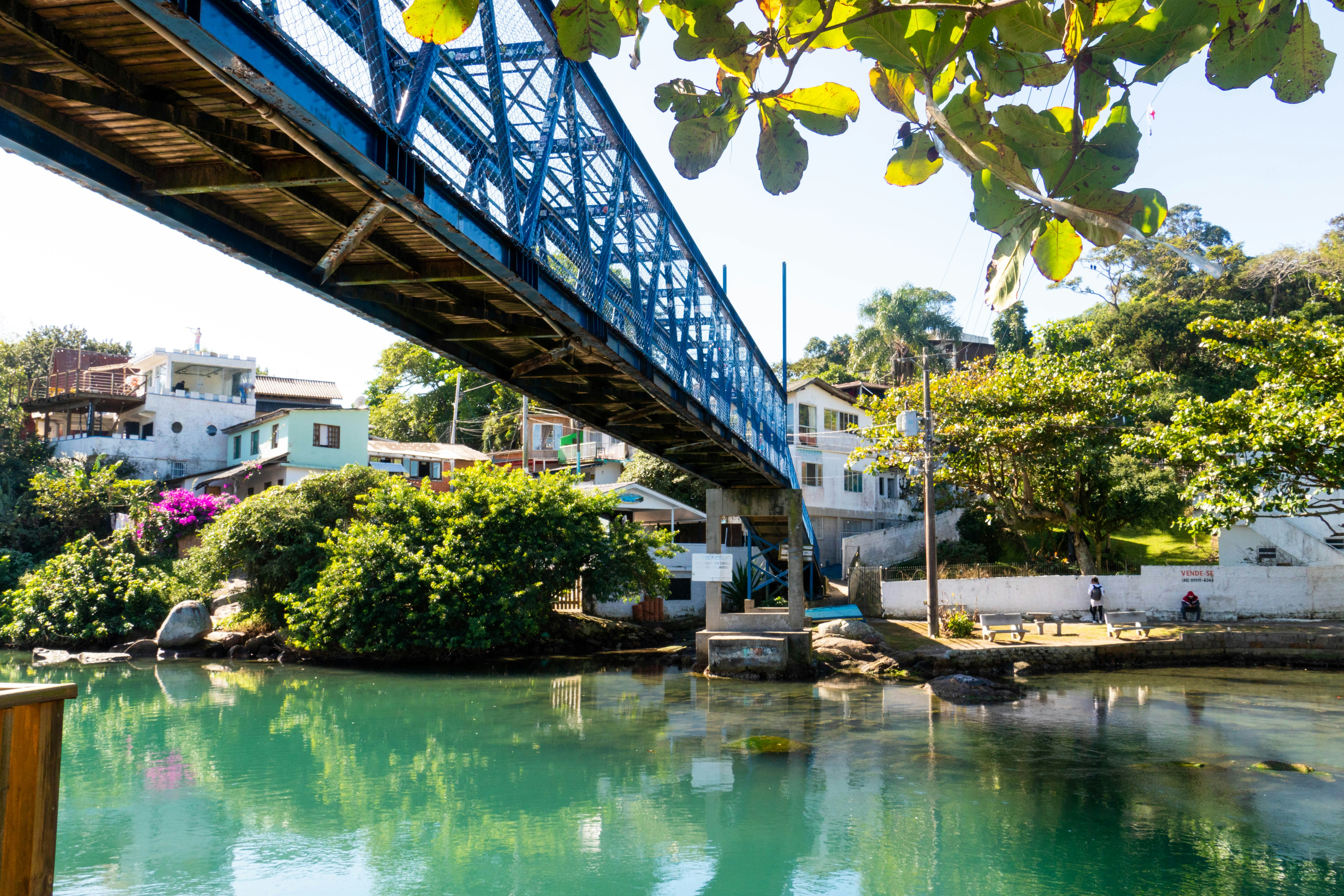 Blue bridge over a tropical river with houses.