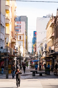People walking down a pedestrian street with buildings.