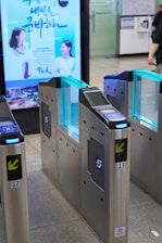 Entrance gates with illuminated blue panels in a station.