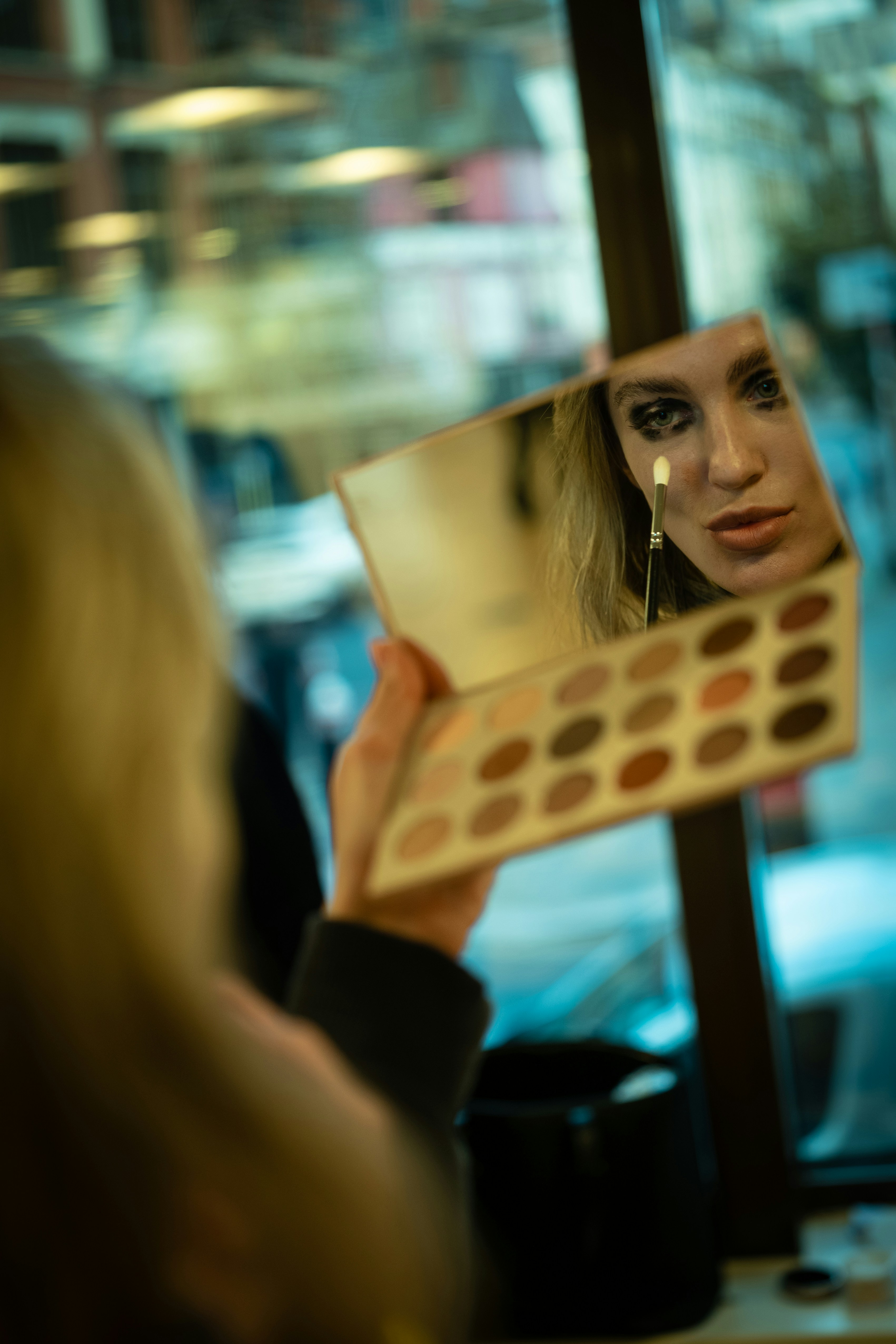 Woman applying dramatic eye makeup in mirror.