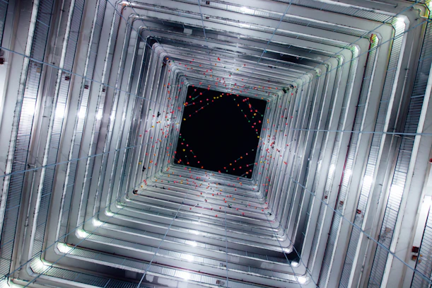 Looking up through a square building shaft with lights.