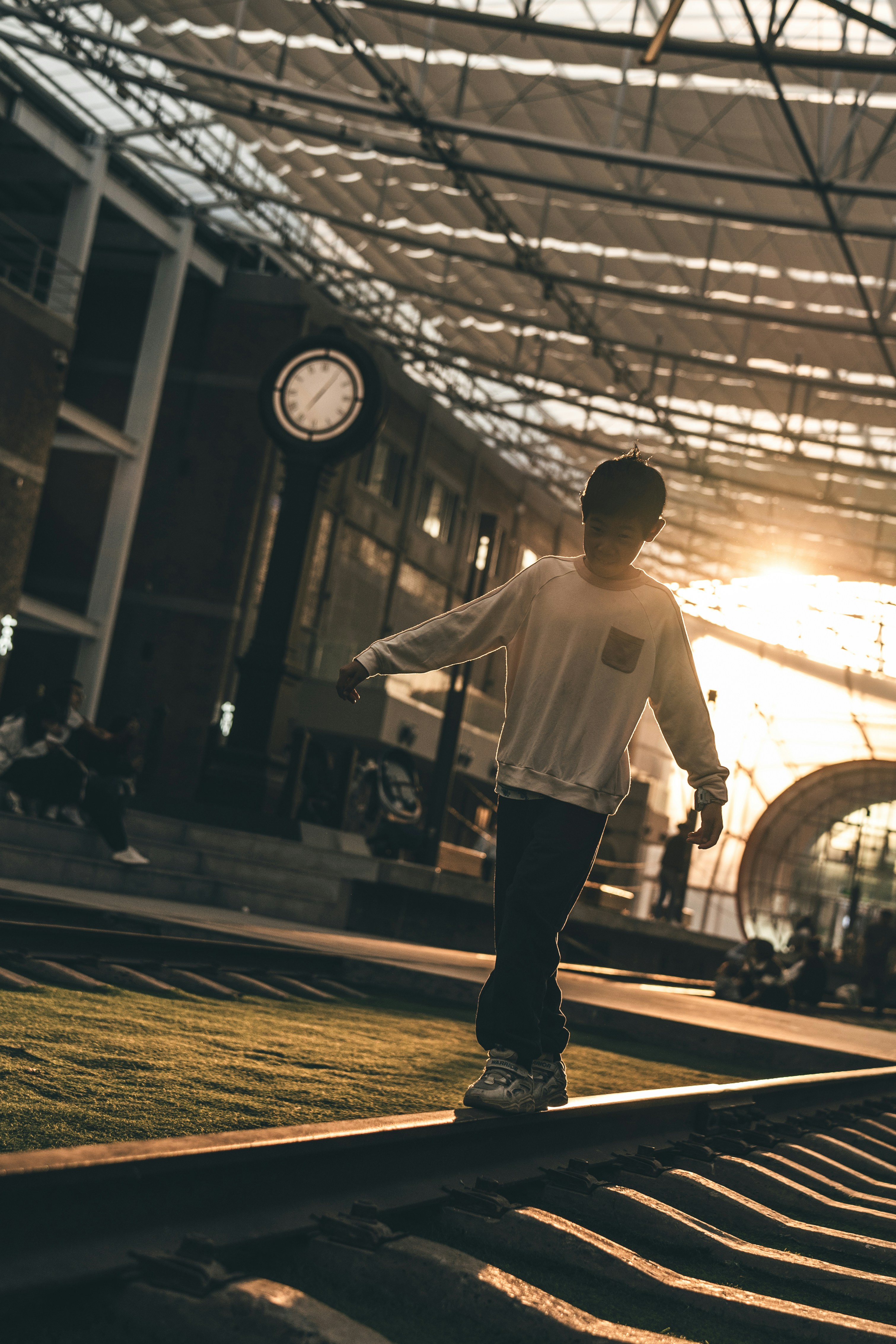 Young man balances on train tracks at sunset