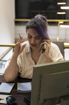 Woman with purple hair talking on phone at desk.