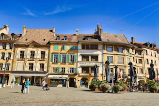 Buildings lining a european town square with people.