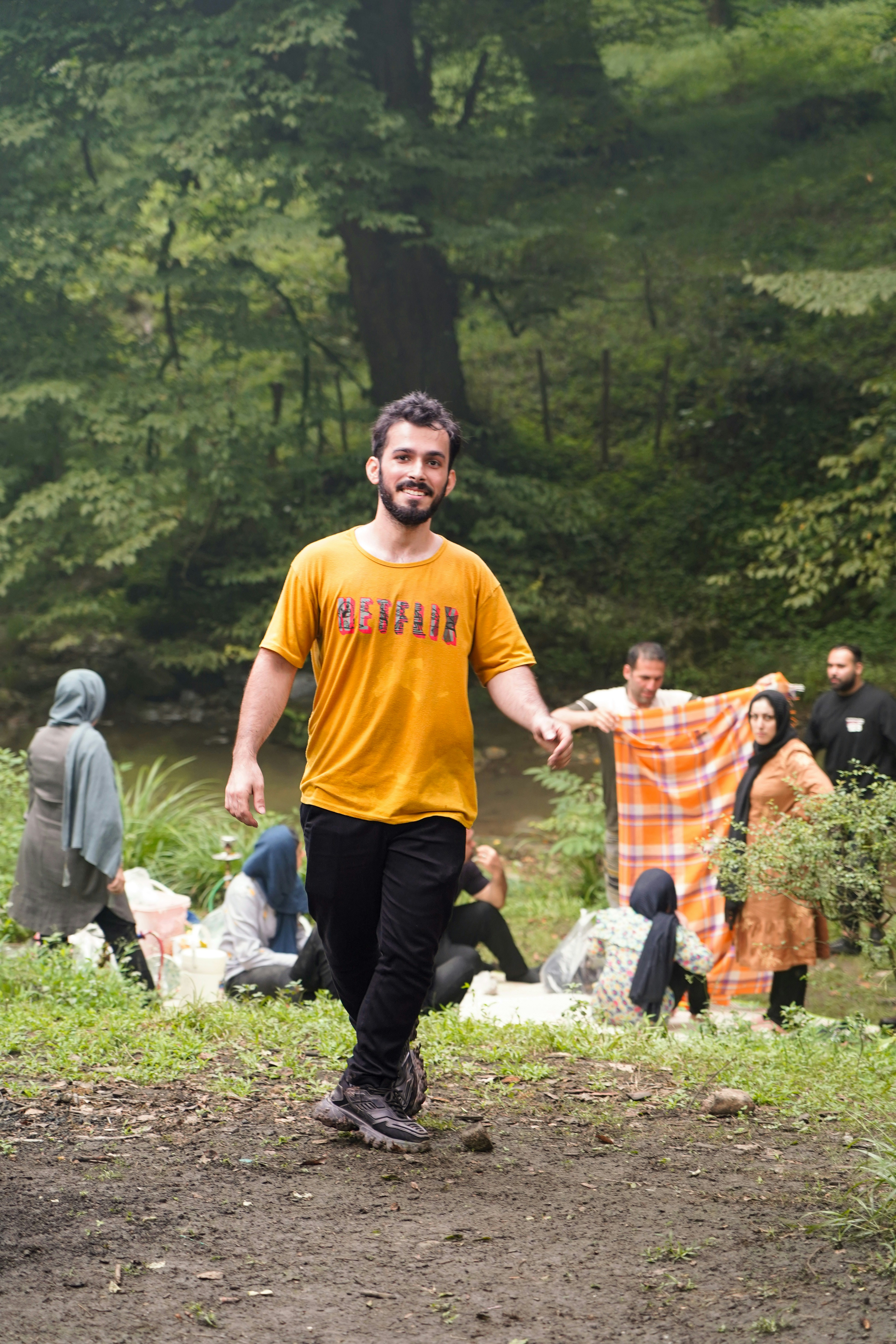 Man walking in a forest with people picnicking