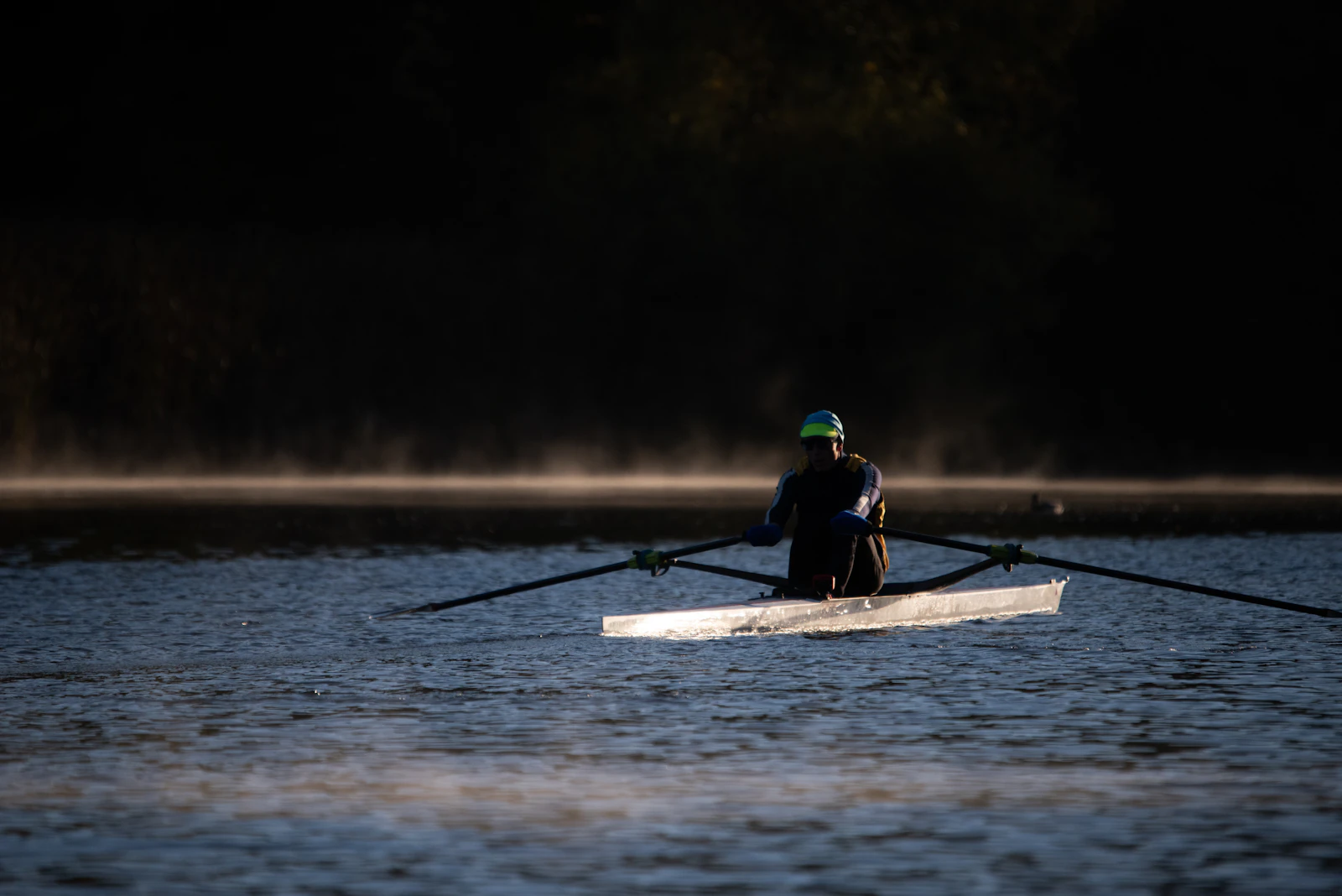 Single sculler on a misty river at dawn