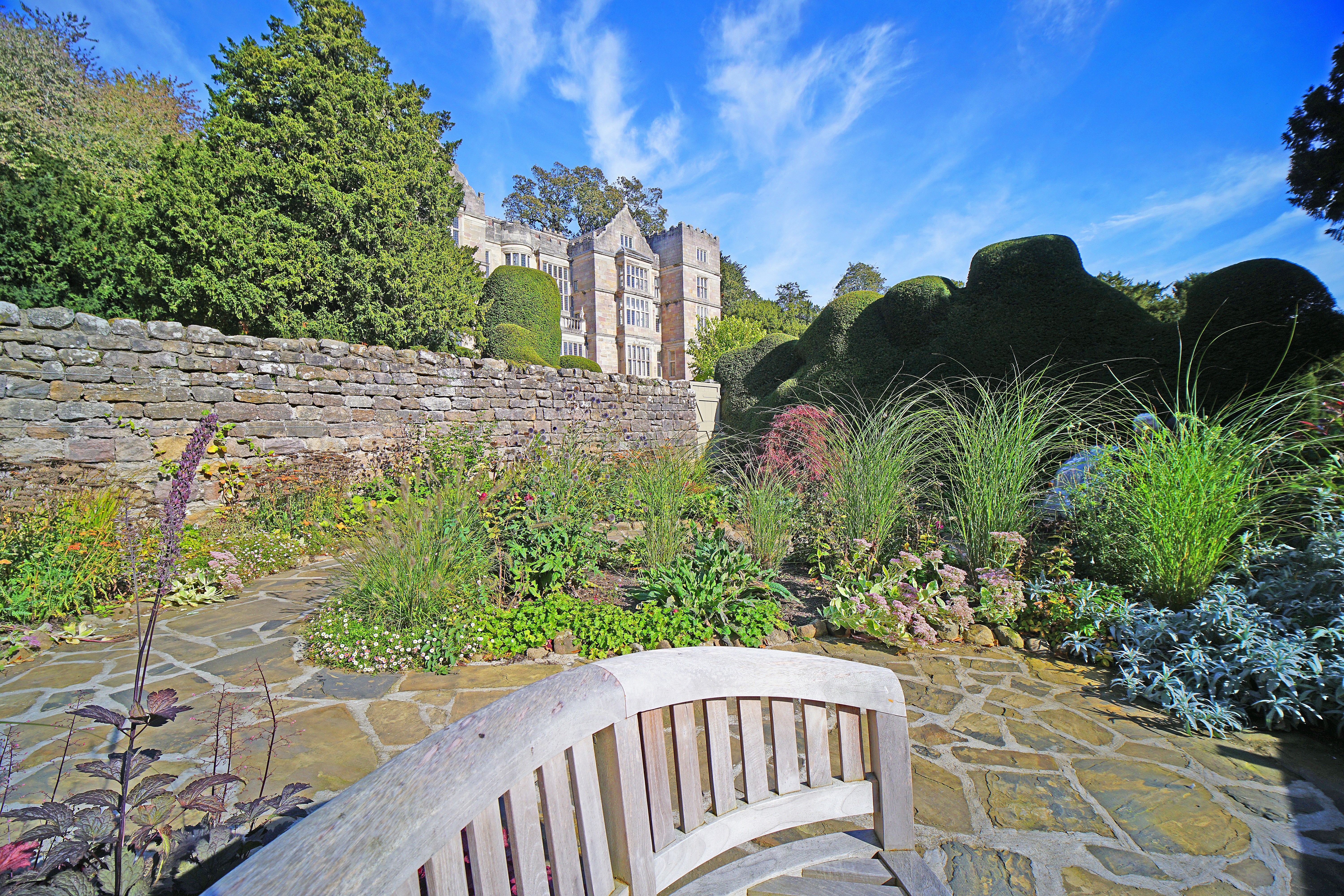 Stone ruins in a lush garden with a wooden bench