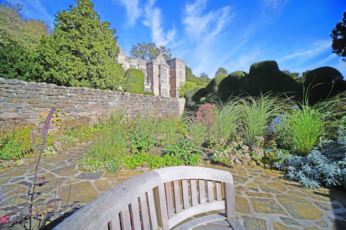 A wooden bench beside stone ruins in a garden