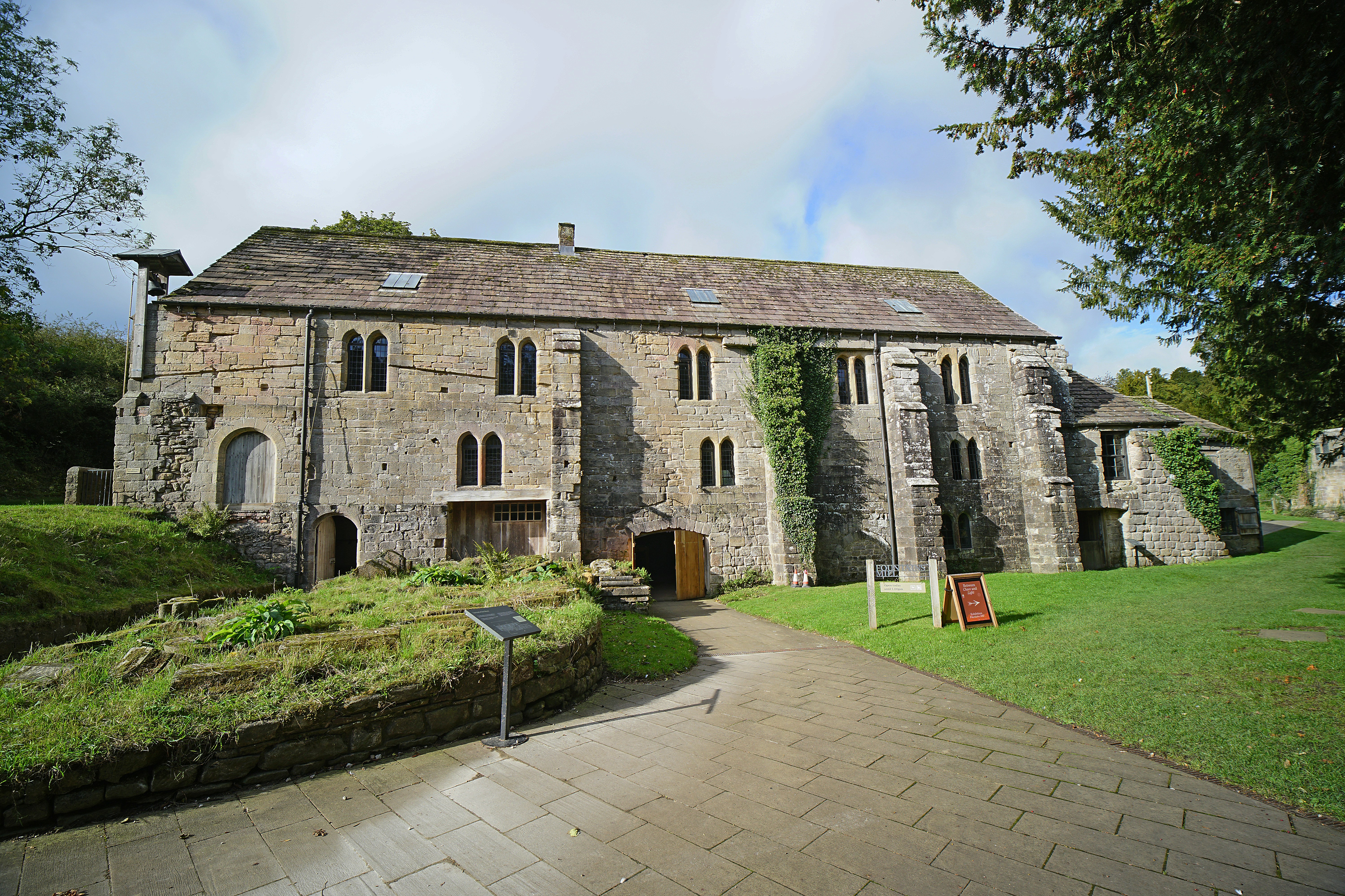 Historic stone building with overgrown greenery and pathway