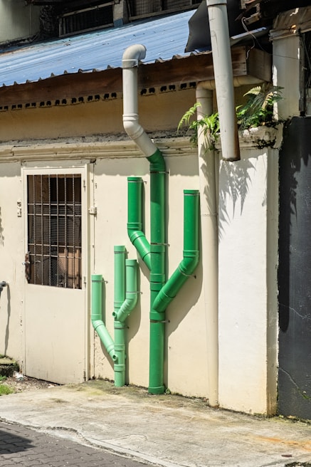Green pipes shaped like a cactus on building wall.
