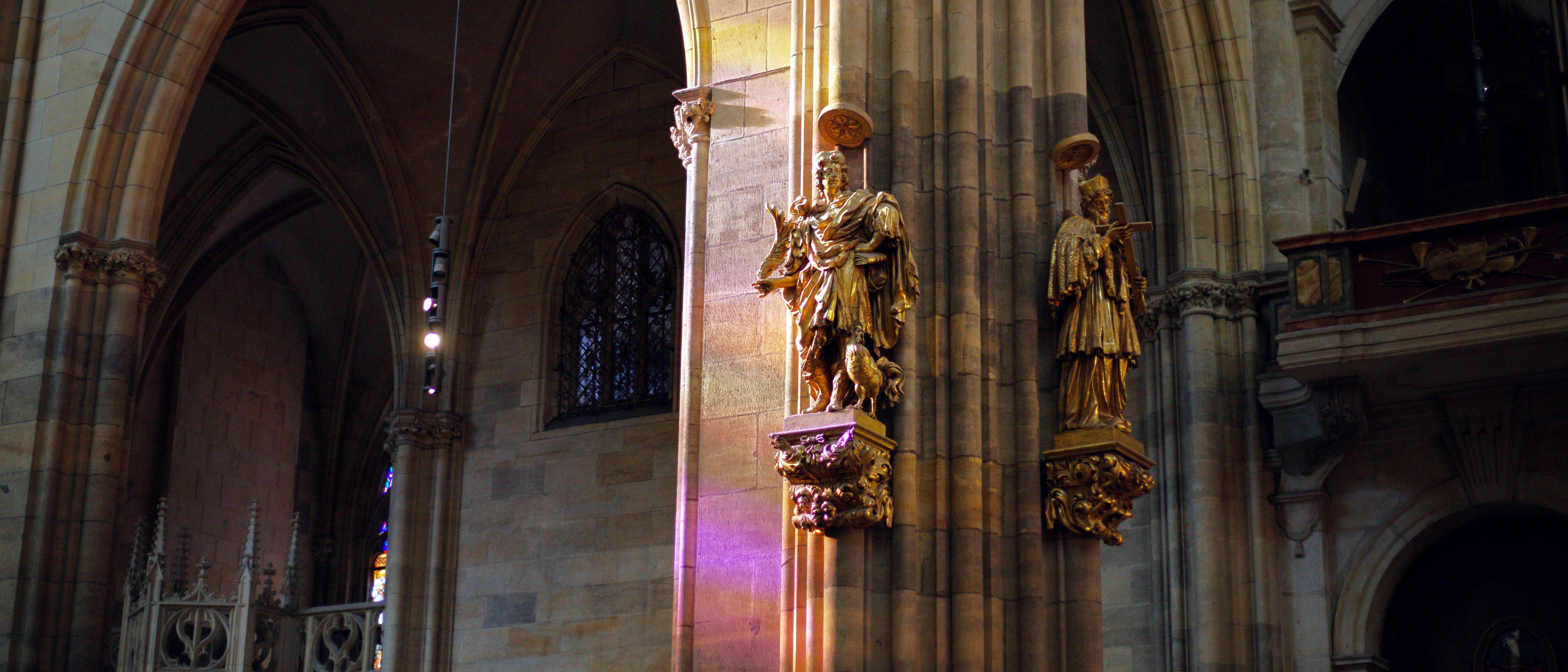 Gothic cathedral interior with ornate statues on pillars.