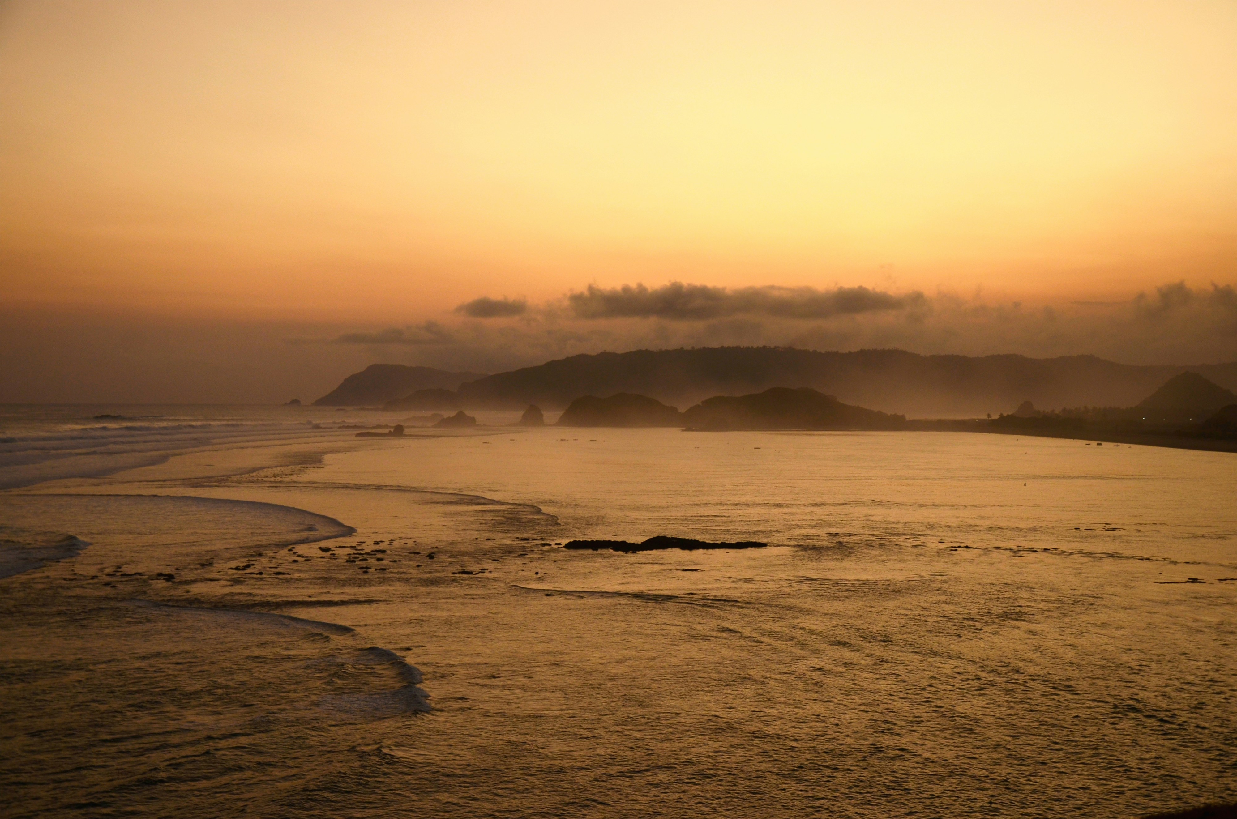 Golden sunset over misty ocean and hills
