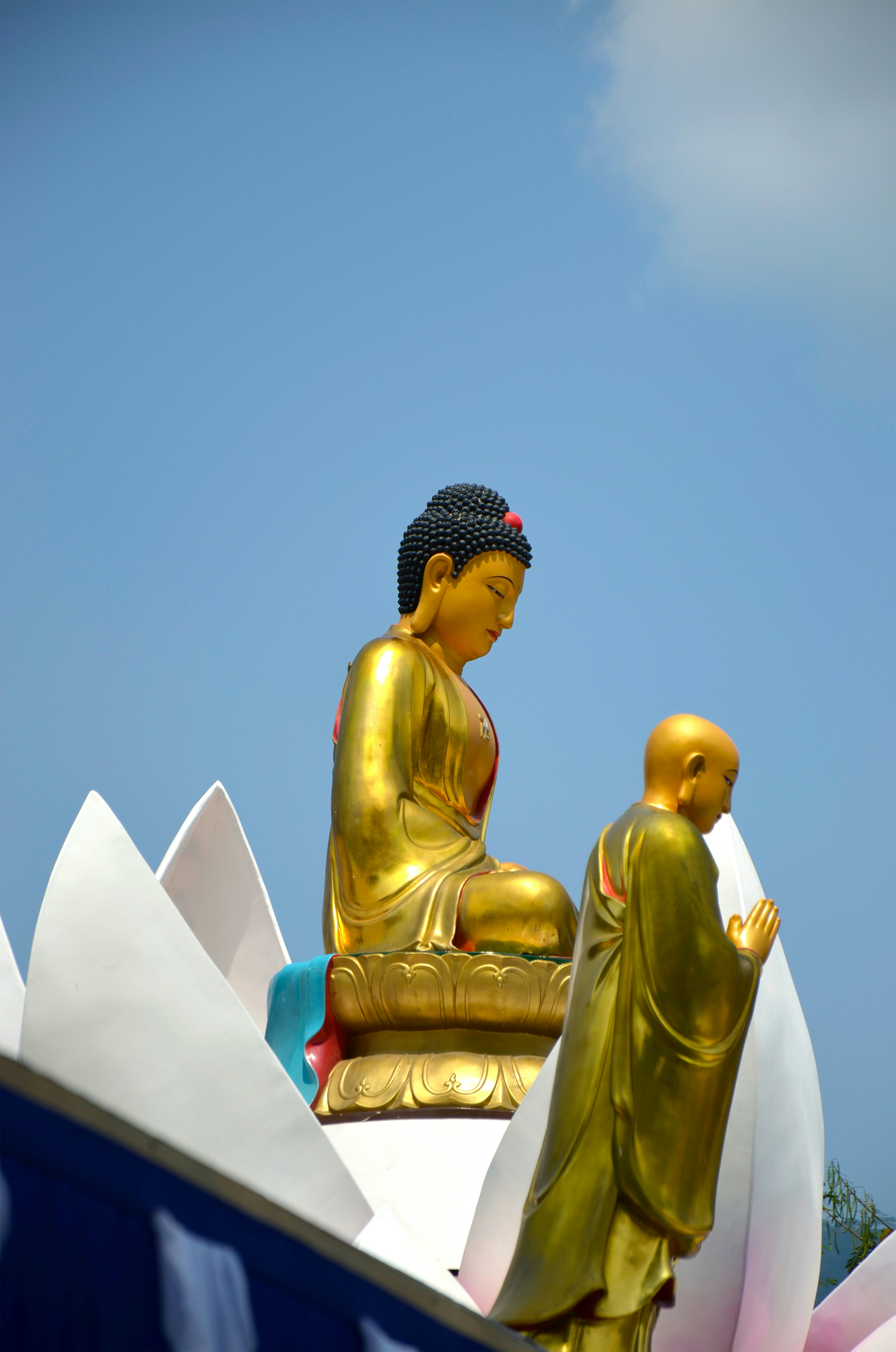 Golden buddha statue with a monk praying