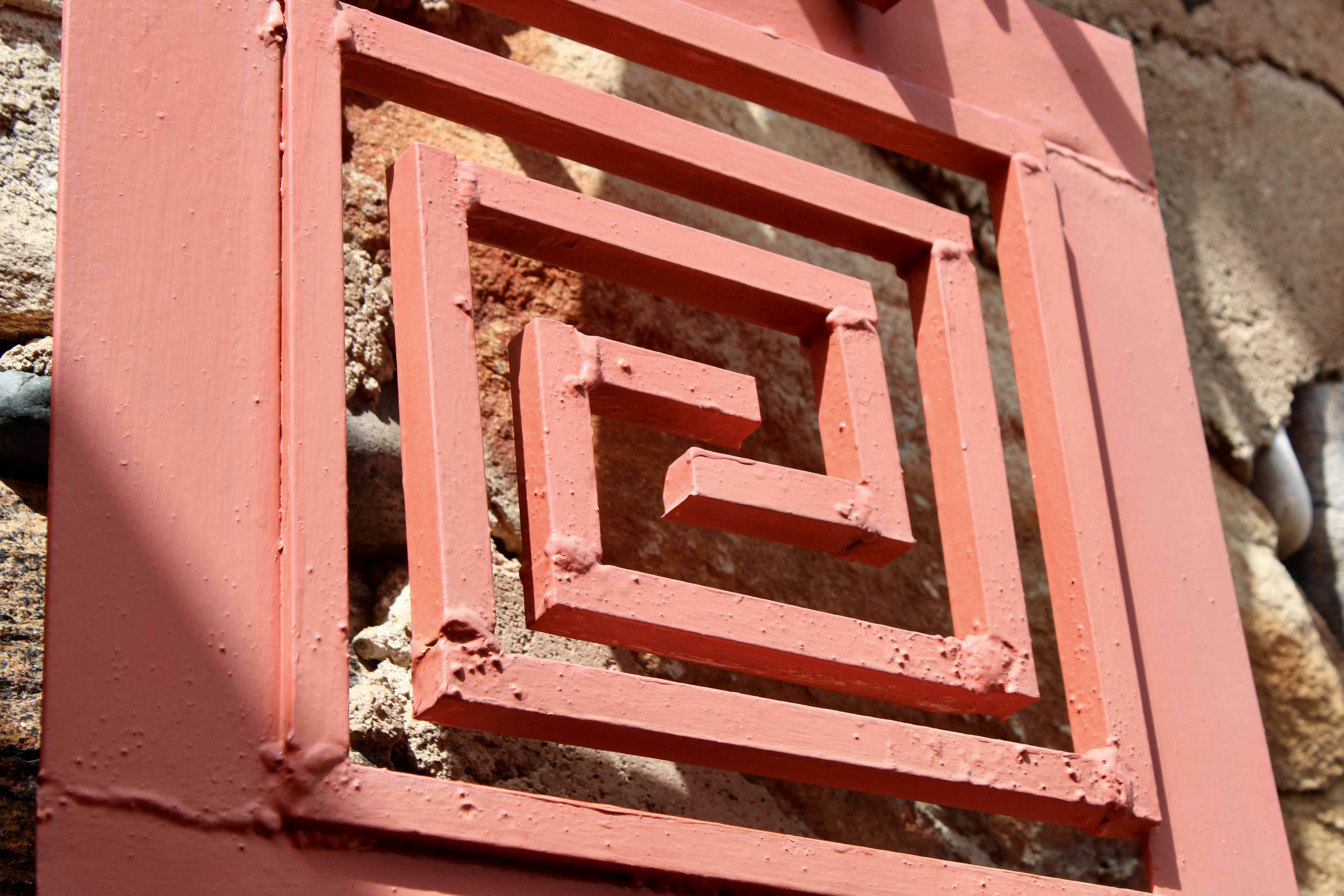 石垣に赤い金属の幾何学模様