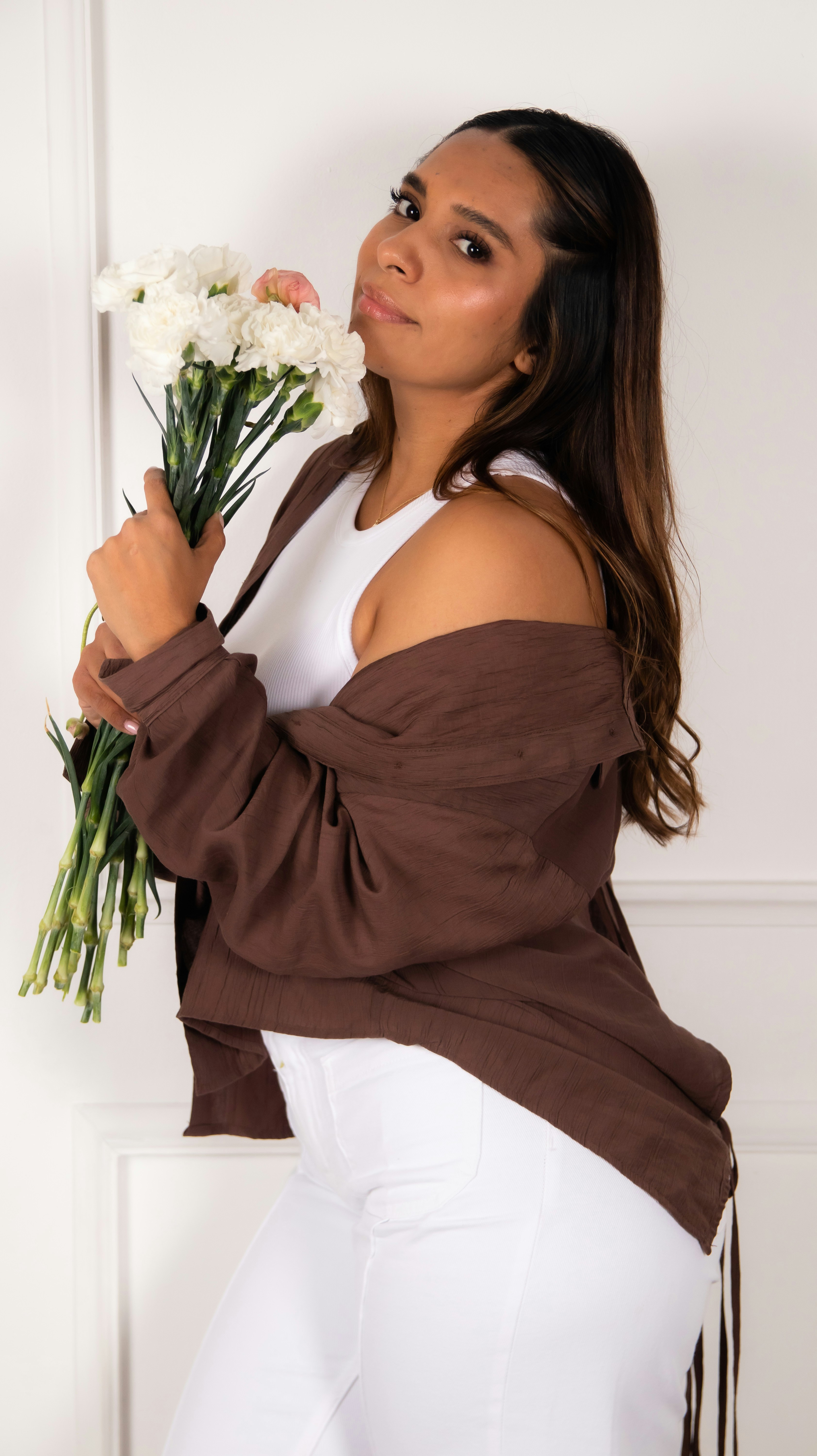 Woman in brown cardigan holding white flowers