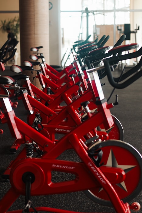 Row of red stationary exercise bikes in gym.