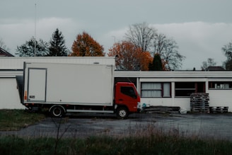Red truck parked next to a white building.