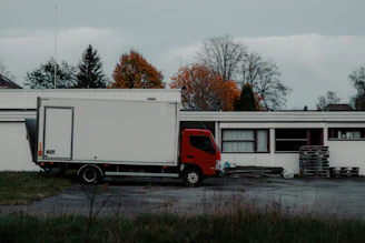 Red truck parked next to a white building