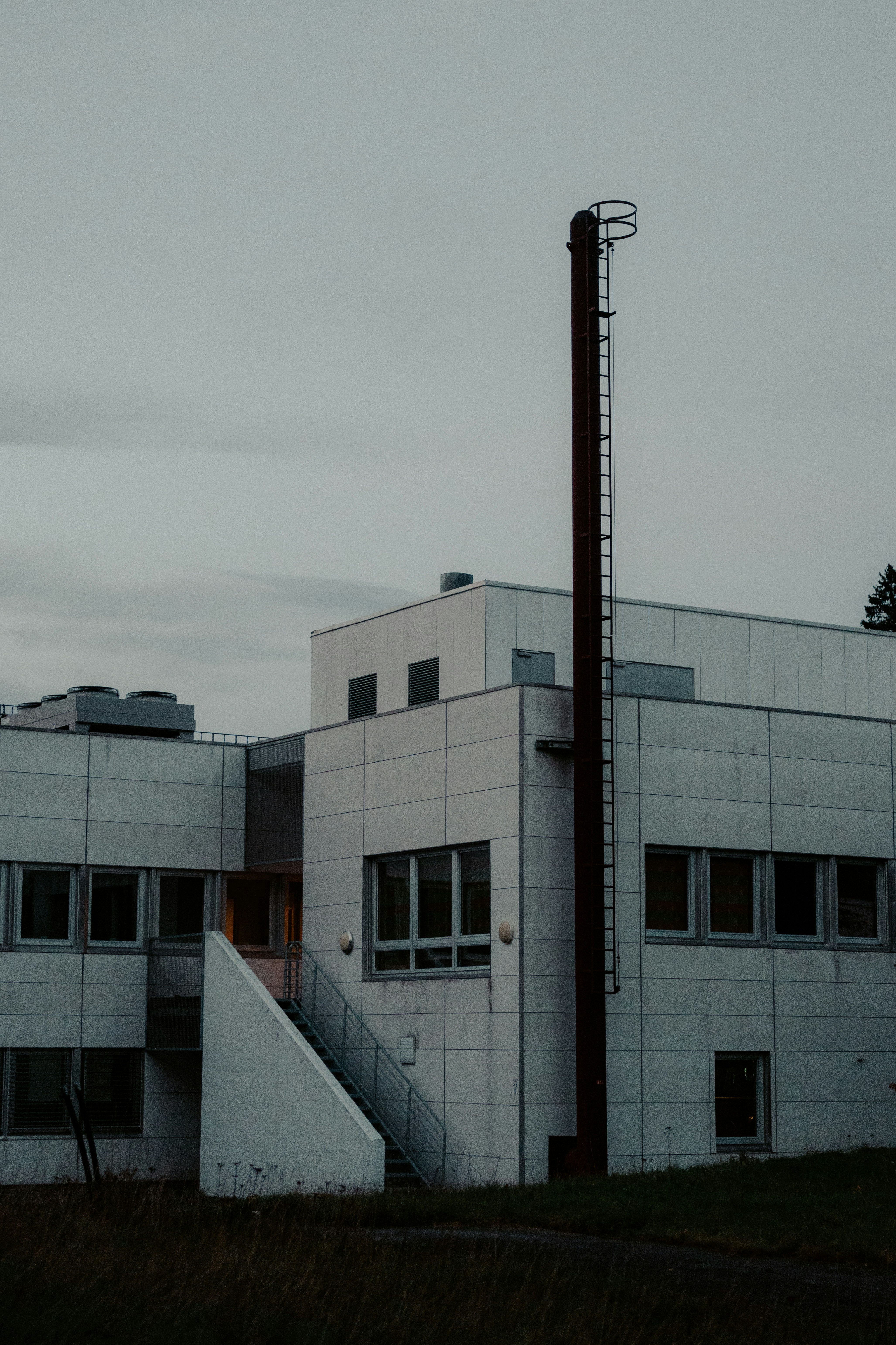 Modern white building with a tall metal pipe
